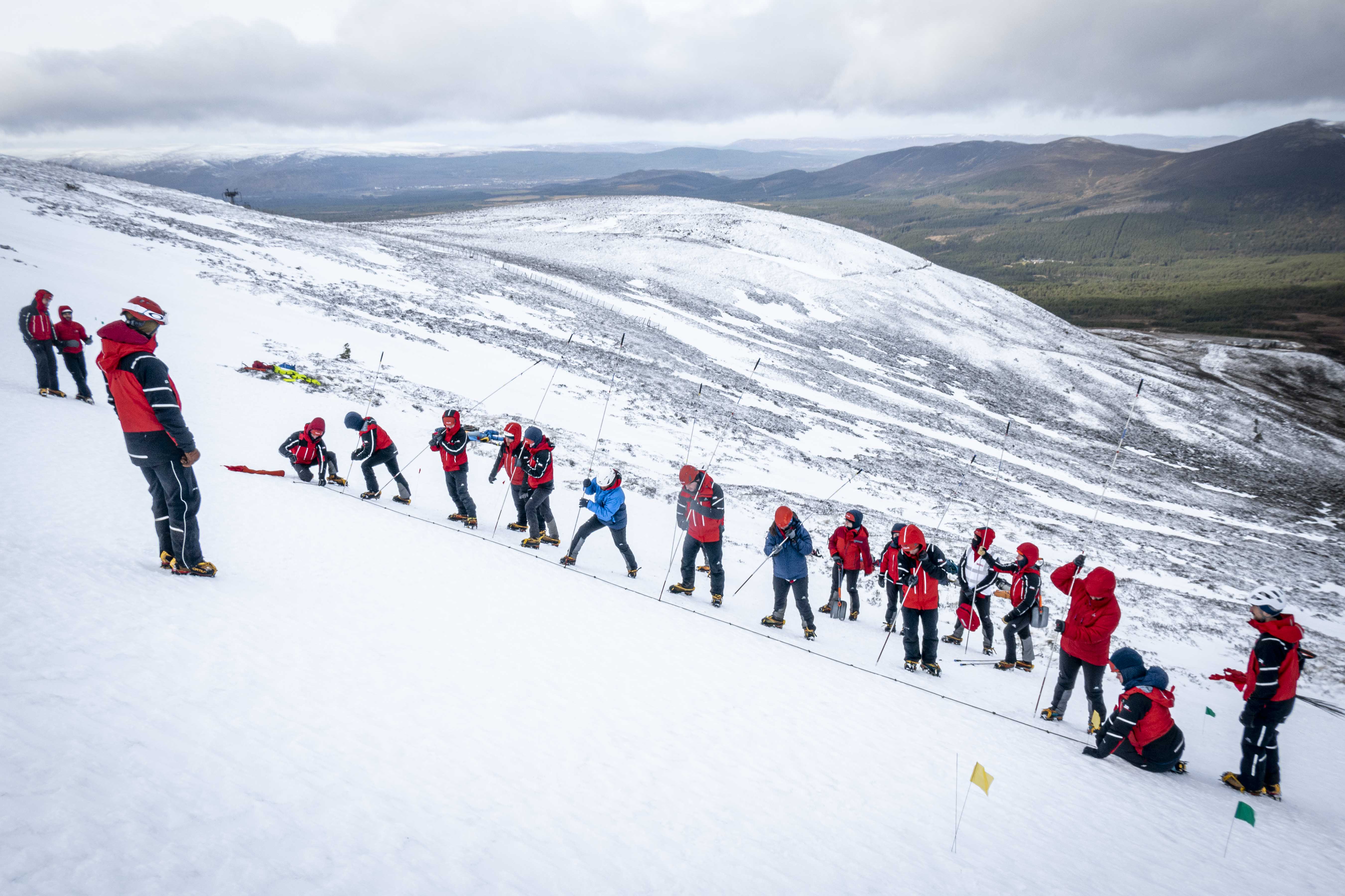 Image shows Mountain Rescue Team on a snowy mountain with climbing equipment.