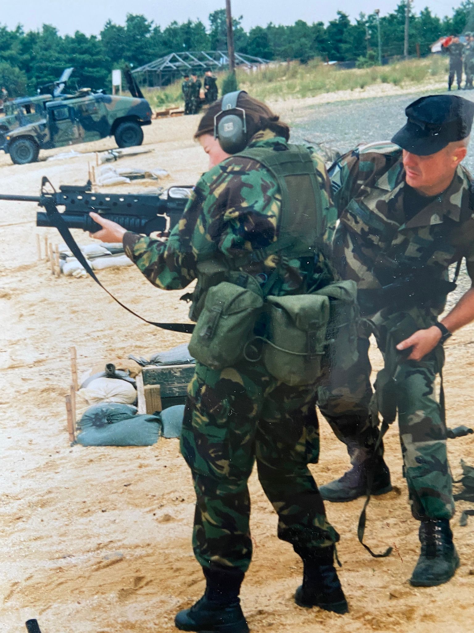 Image shows training camp with RAF aviator aiming a rifle and gunner vehicles.