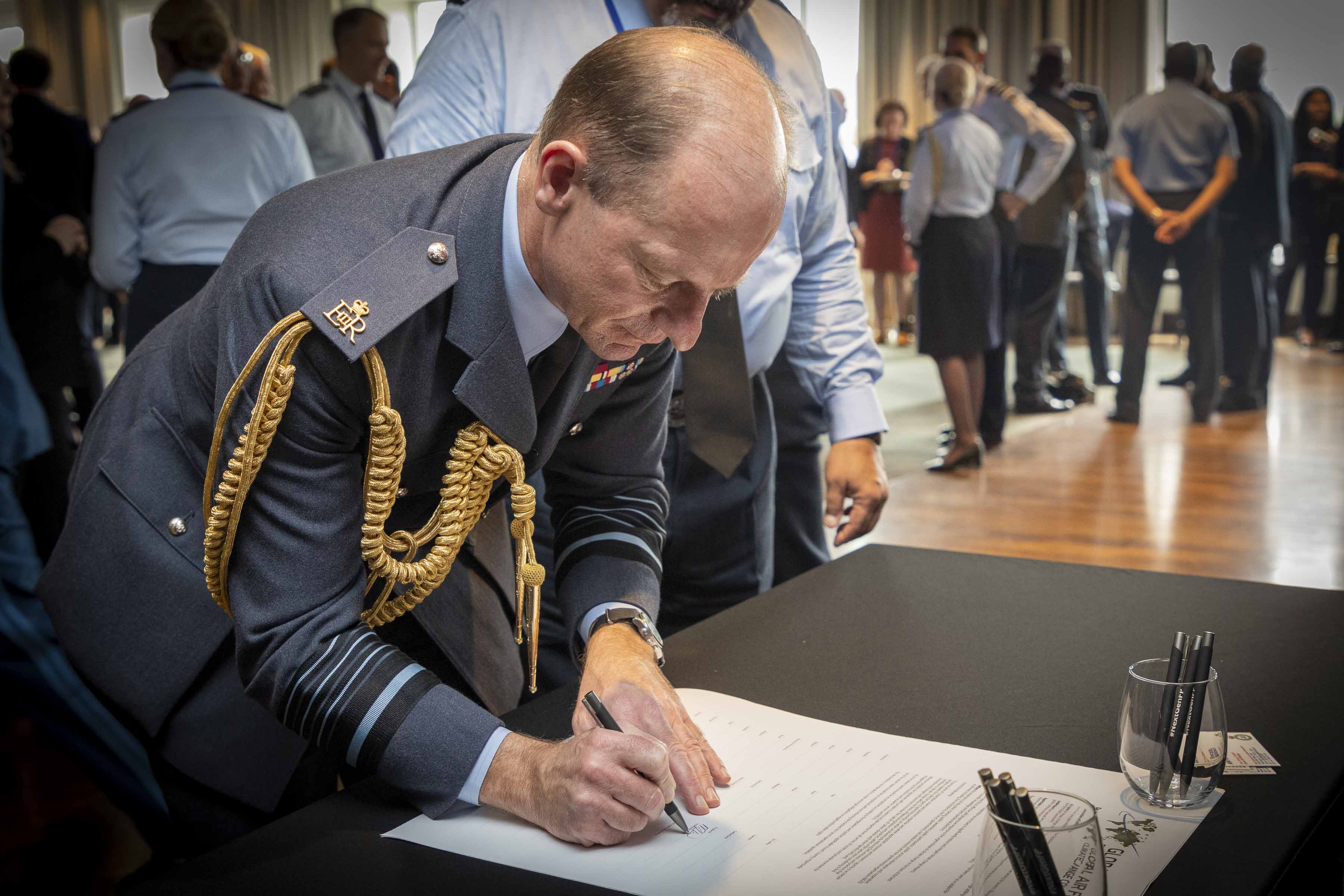Image shows the Chief of the Air Staff signing document.