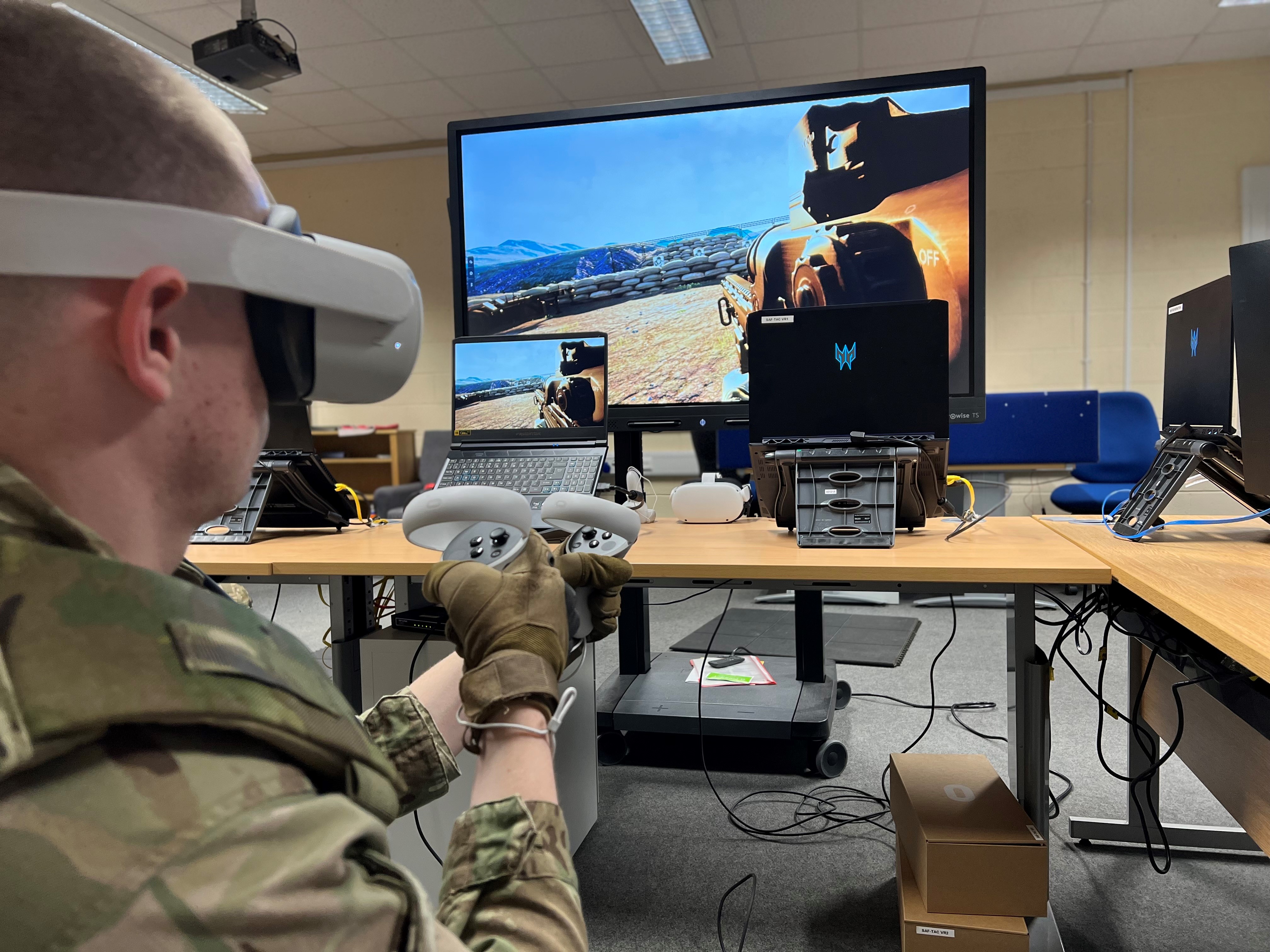 Personnel wear Virtual Reality headsets and use equipment. Computers and desks in background.