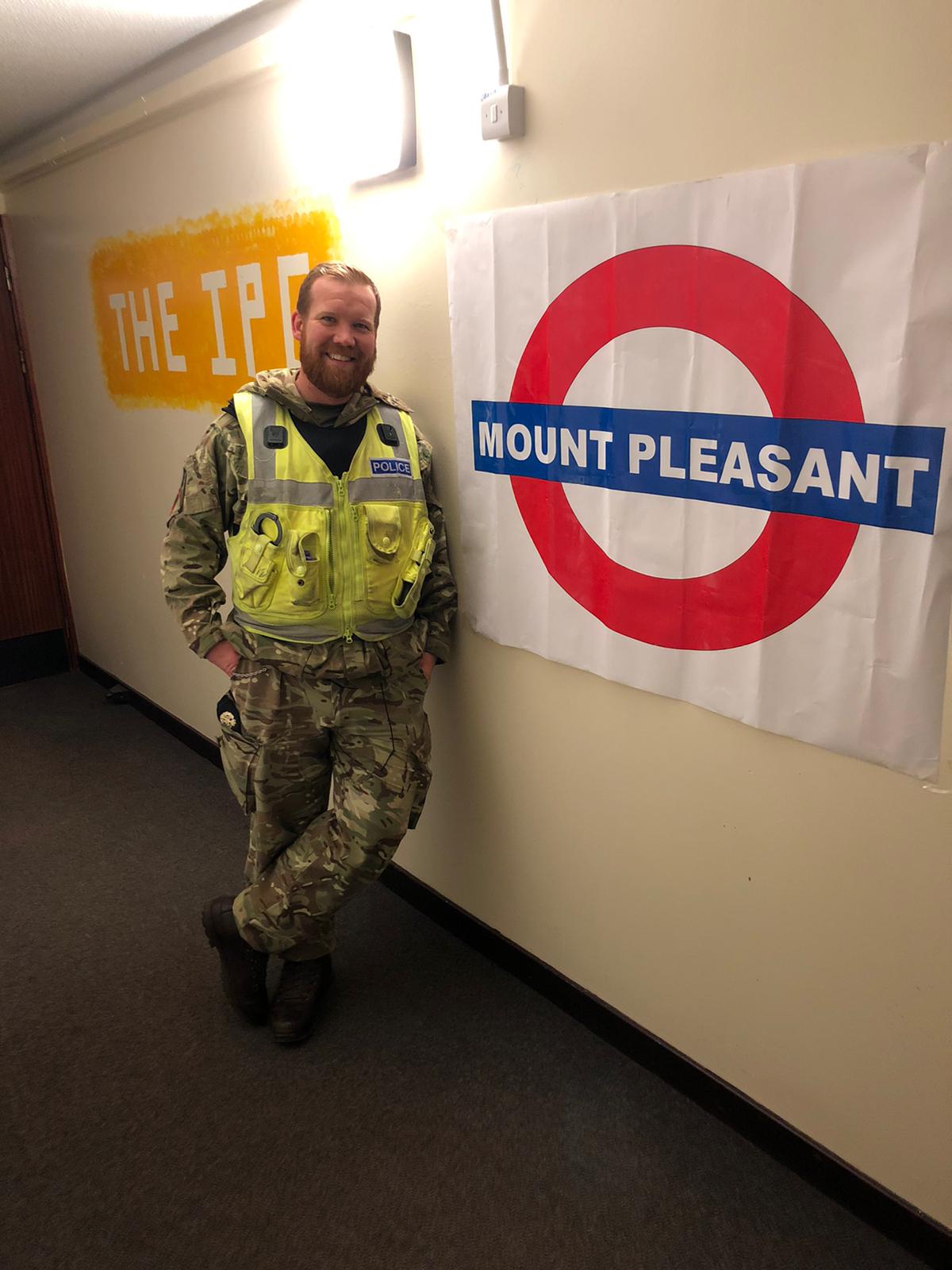 RAF Policeman stands by Mount Pleasant sign.
