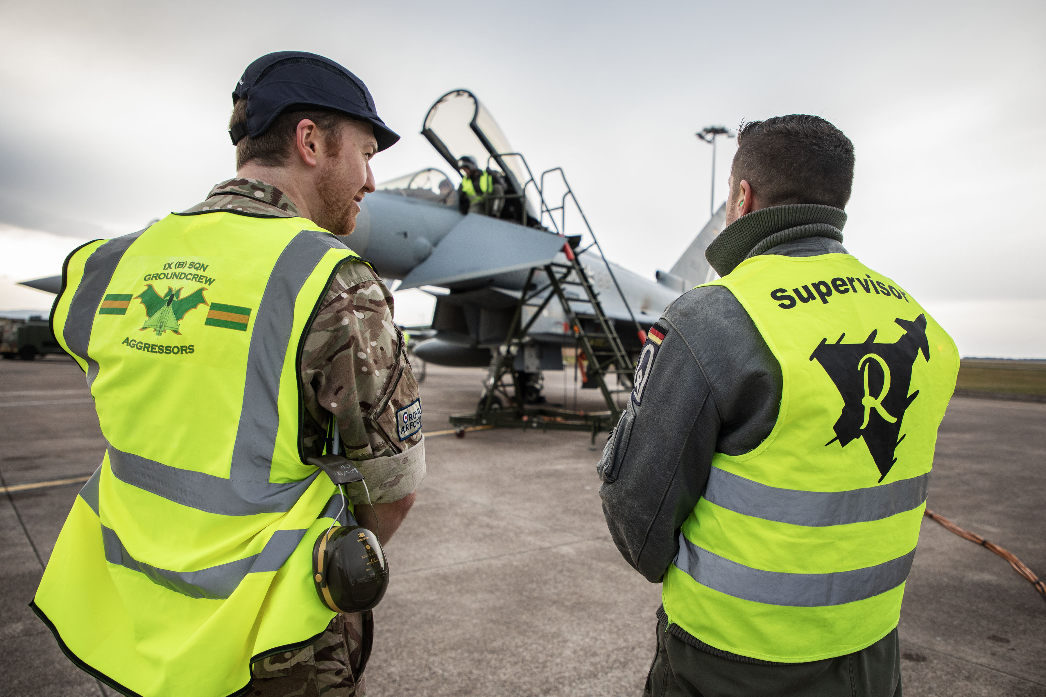 Image shows RAF aviators looking towards a Typhoon on the airfield.