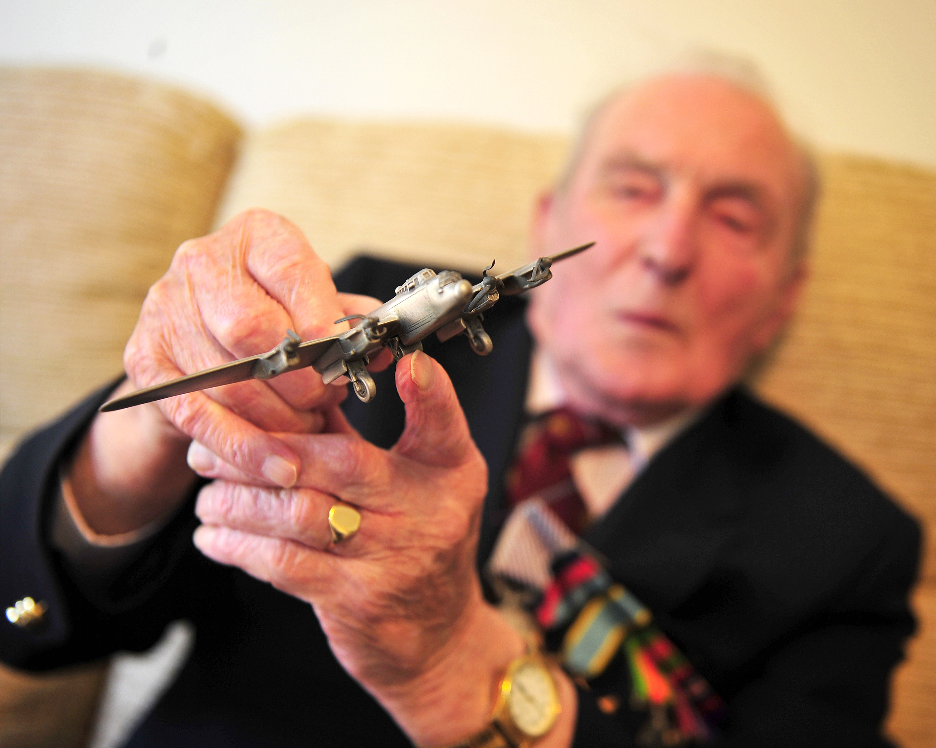 Image shows RAF Veteran holding model Lancaster Bomber.