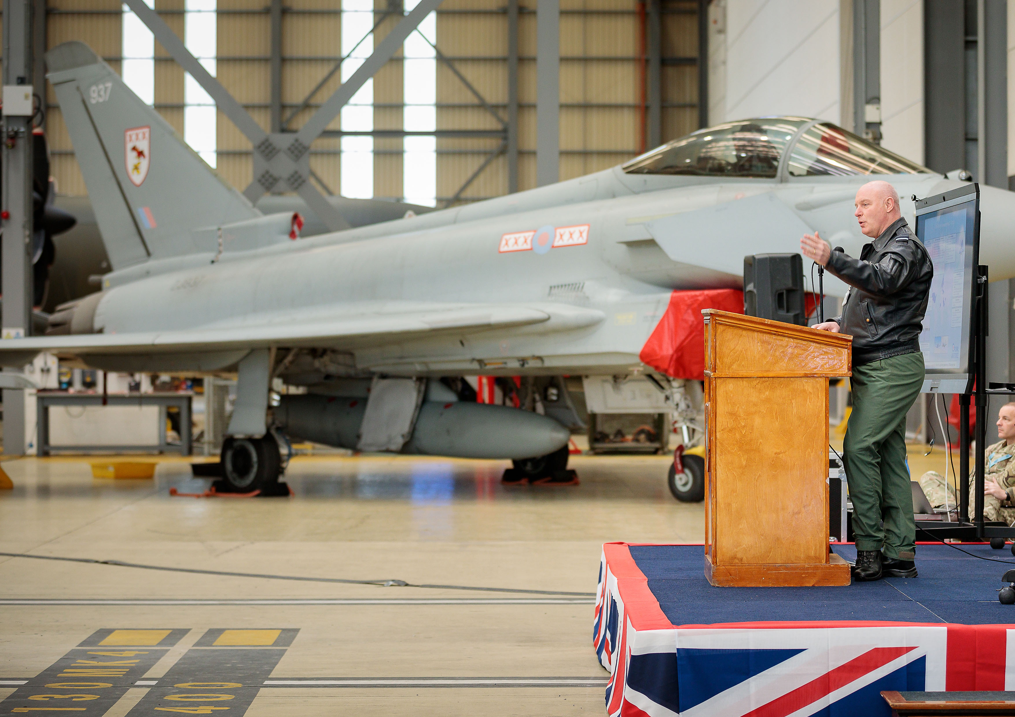 Image shows Typhoon in the hangar by RAF aviator presenting on a stage.
