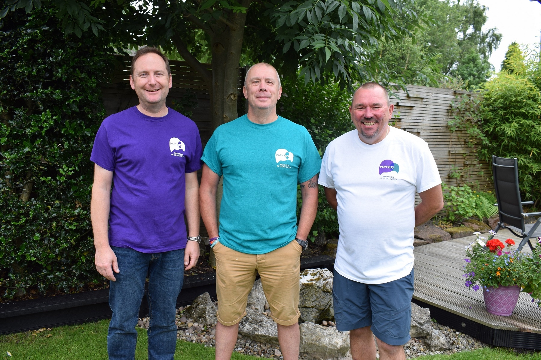 Image shows three dads smiling in a garden.