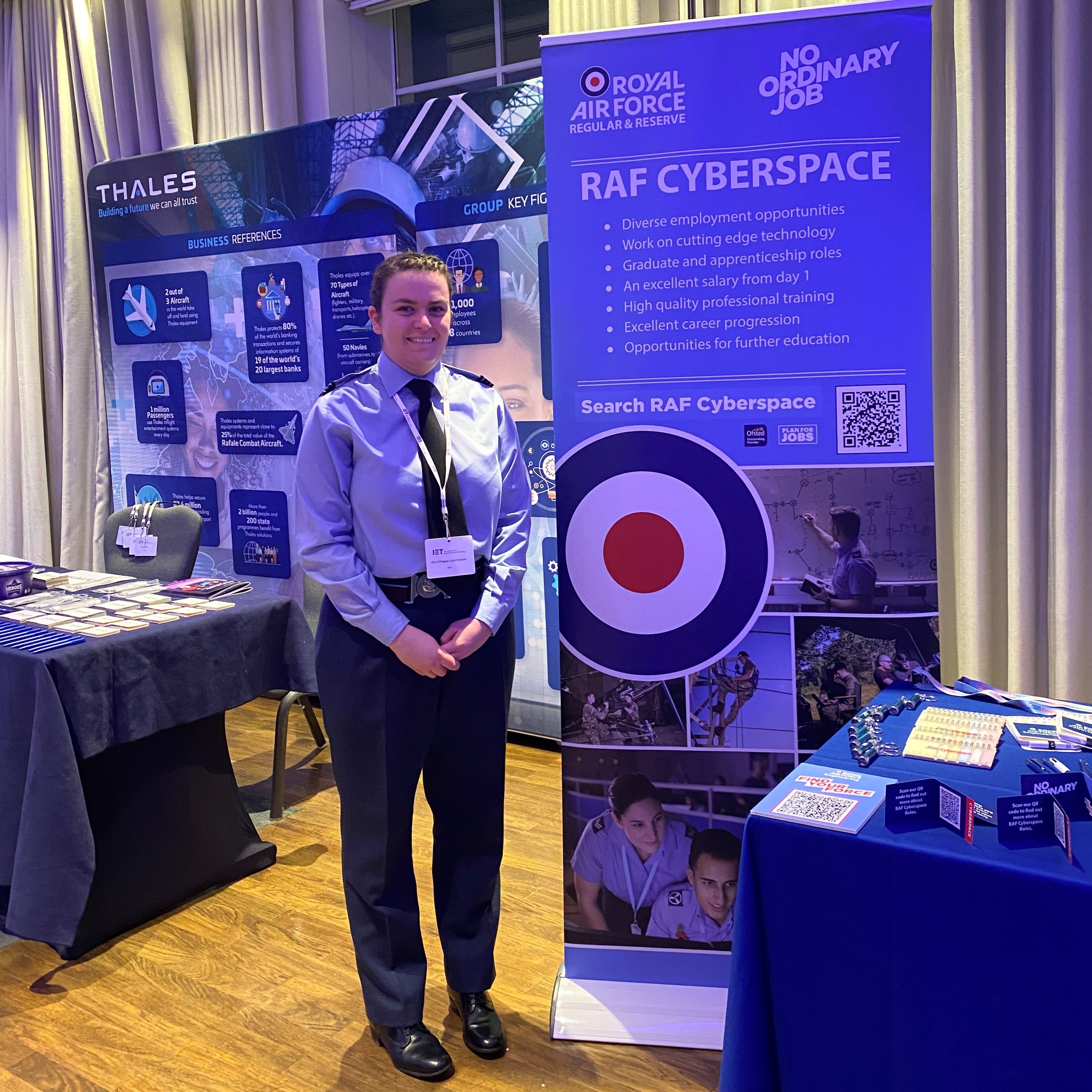 Image shows RAF aviator standing by a RAF careers fair stand.. 