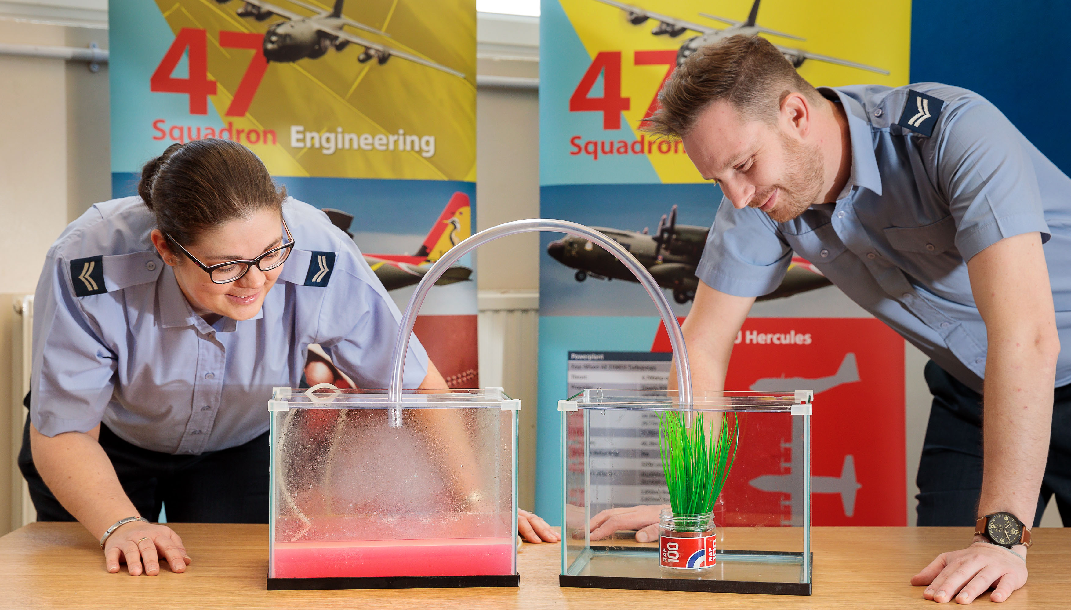 Image shows aviators performing experiment with two glass boxes and plant.