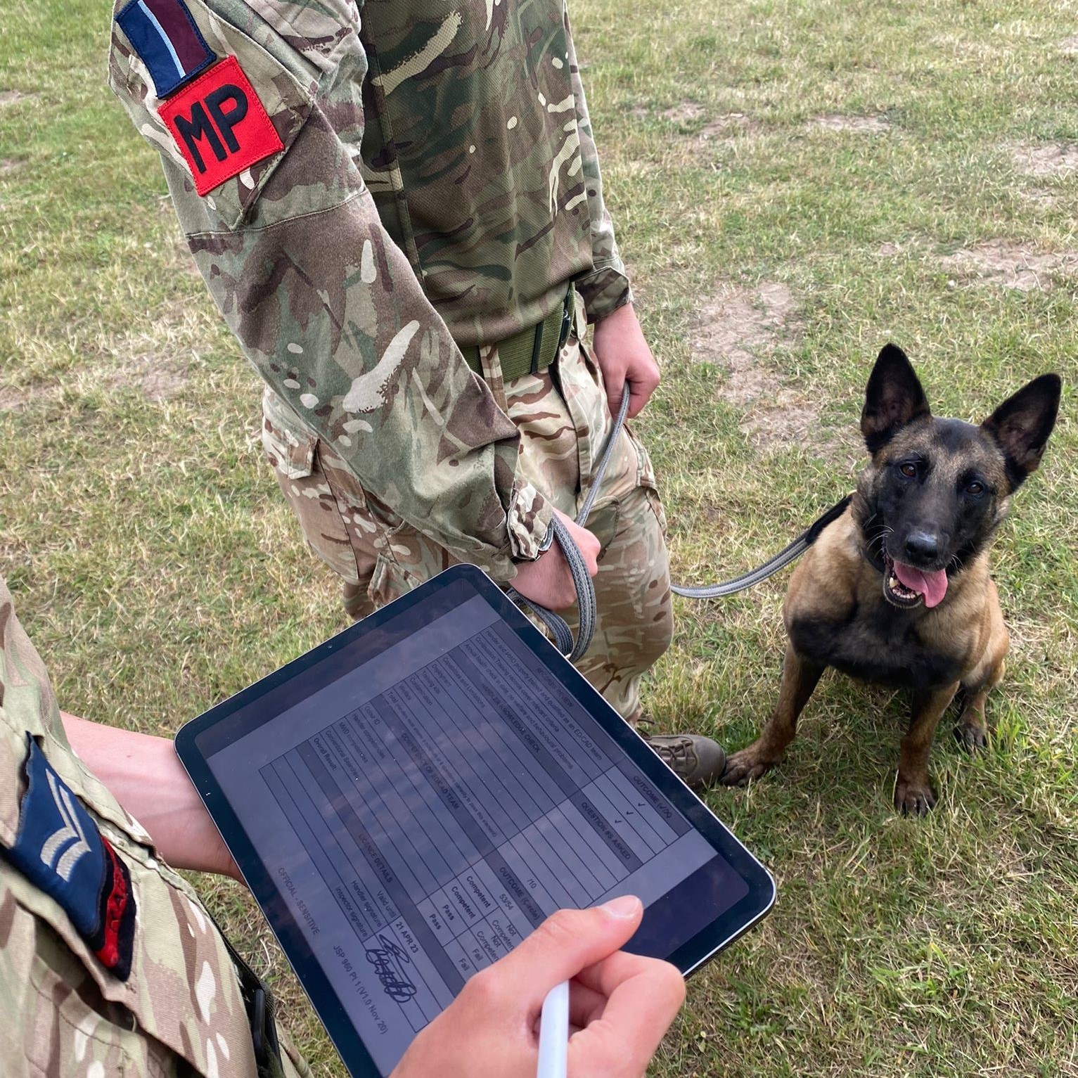 Image shows RAF Police using I-Pad and standing with their military working dog.