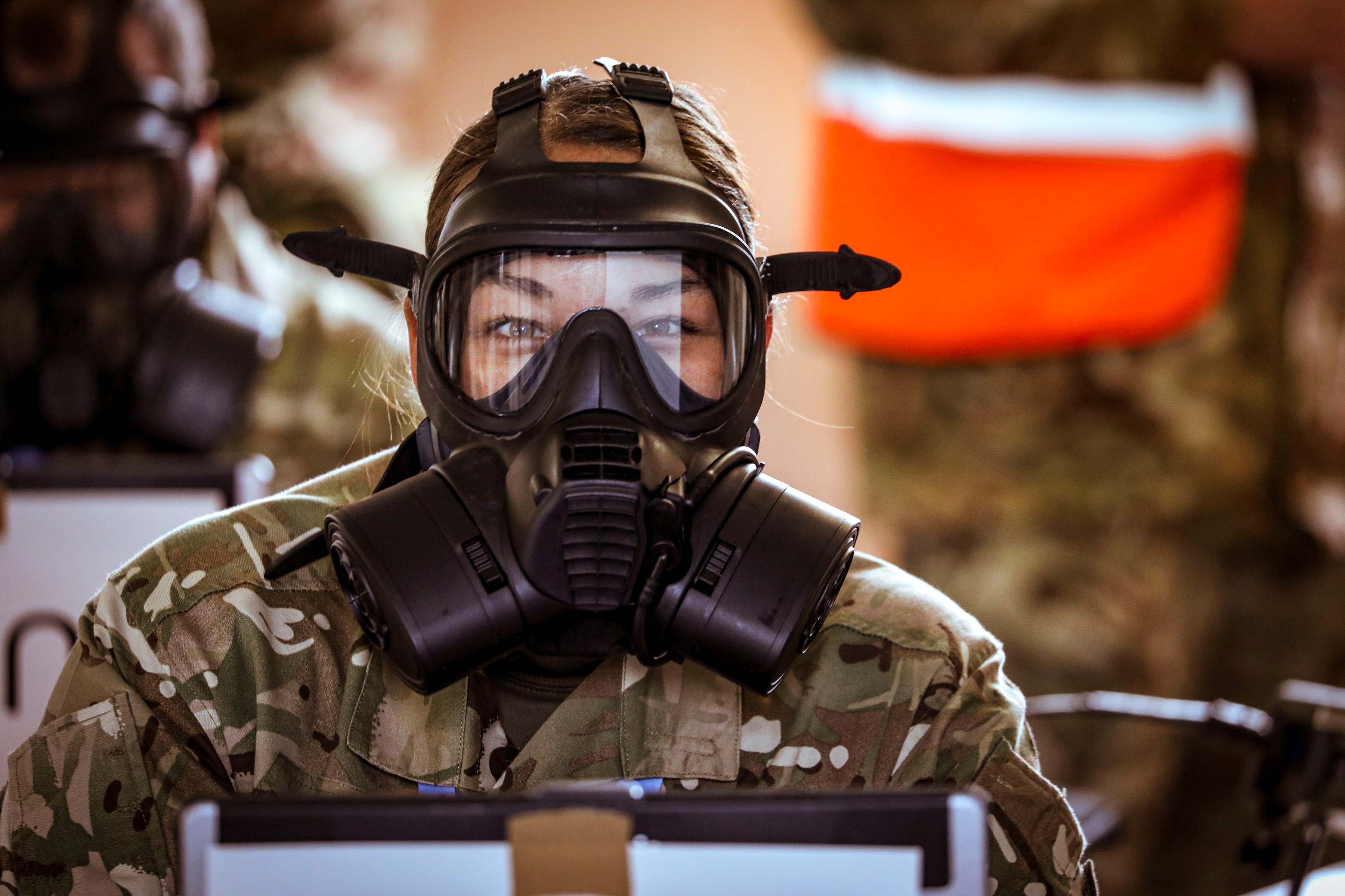 Image shows RAF aviator wearing a respiratory gas mask at a table..