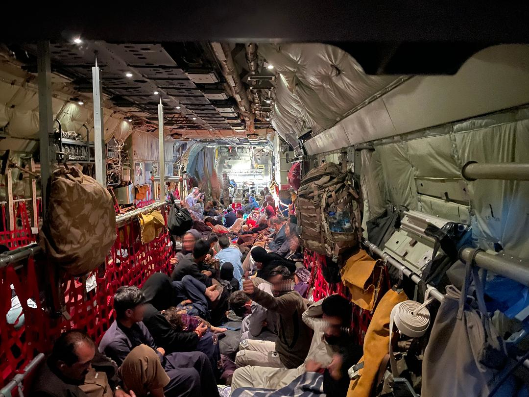 Image shows inside of cargo hold of RAF Hercules with RAF aviators and Afghan evacuees.