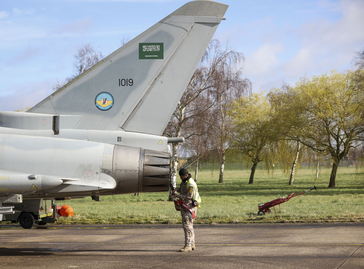 Image shows pilot checking fighter jet on the airfield.