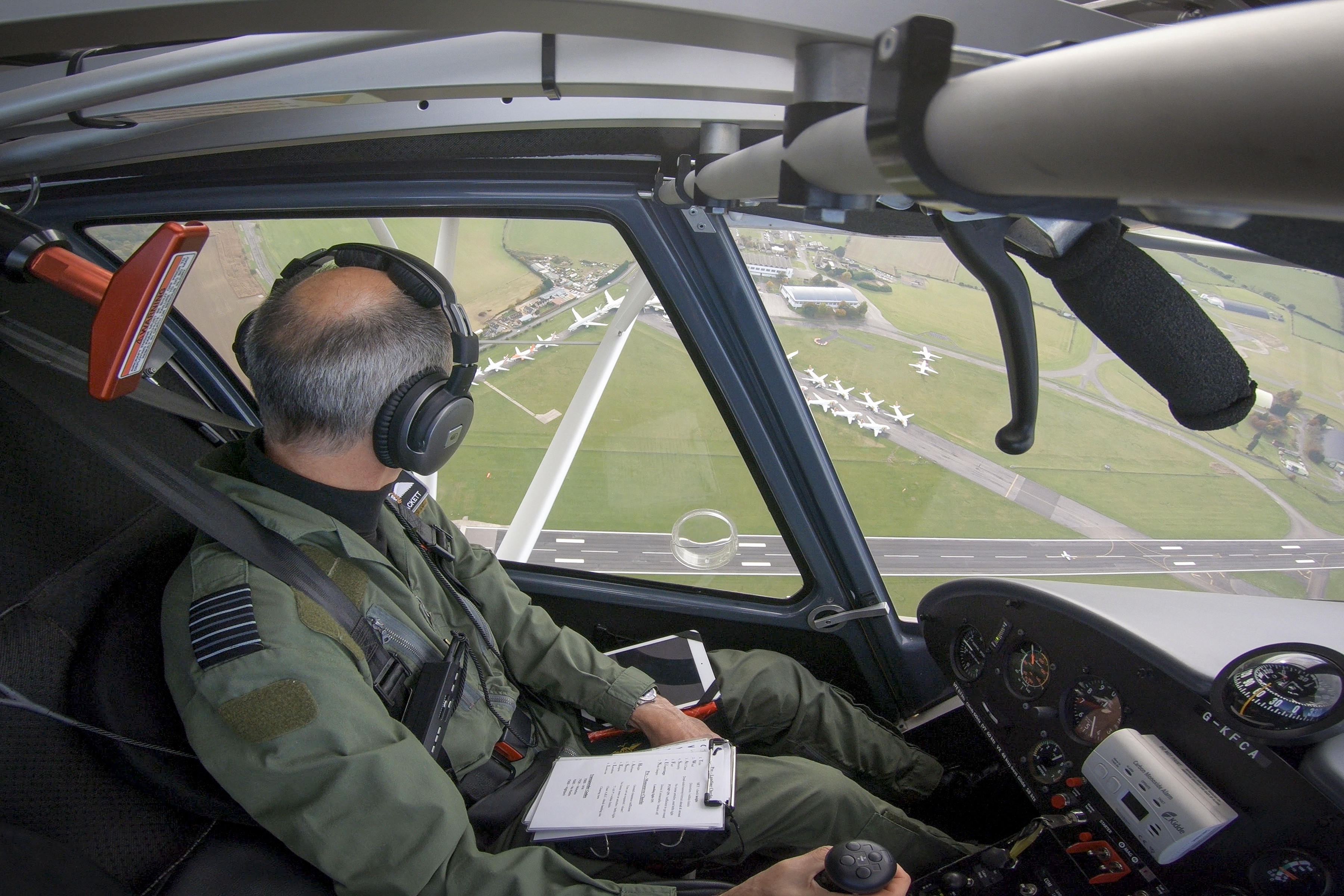 Image shows pilot looking out of cockpit to airfield.