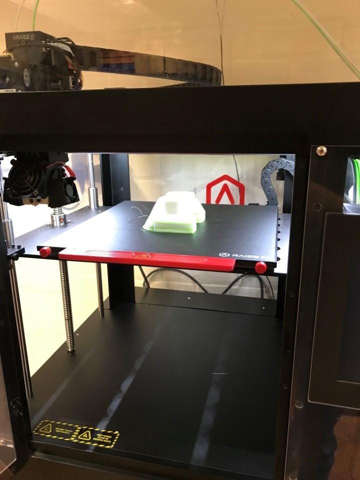 Image shows a 3D printer with plastic model inside.