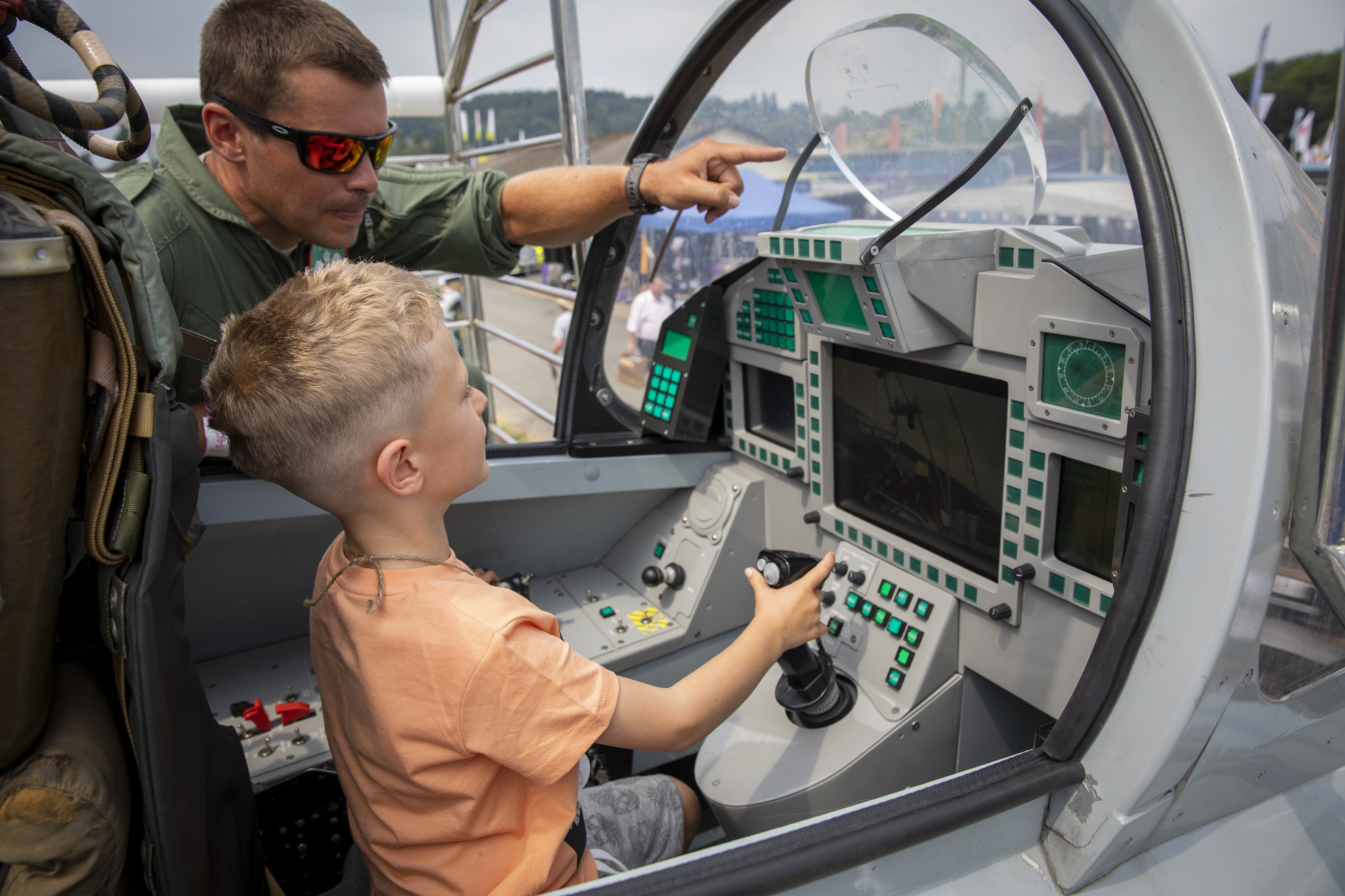 Image shows child in a Typhoon cockpit simulator with RAF aviator pointing to screen.