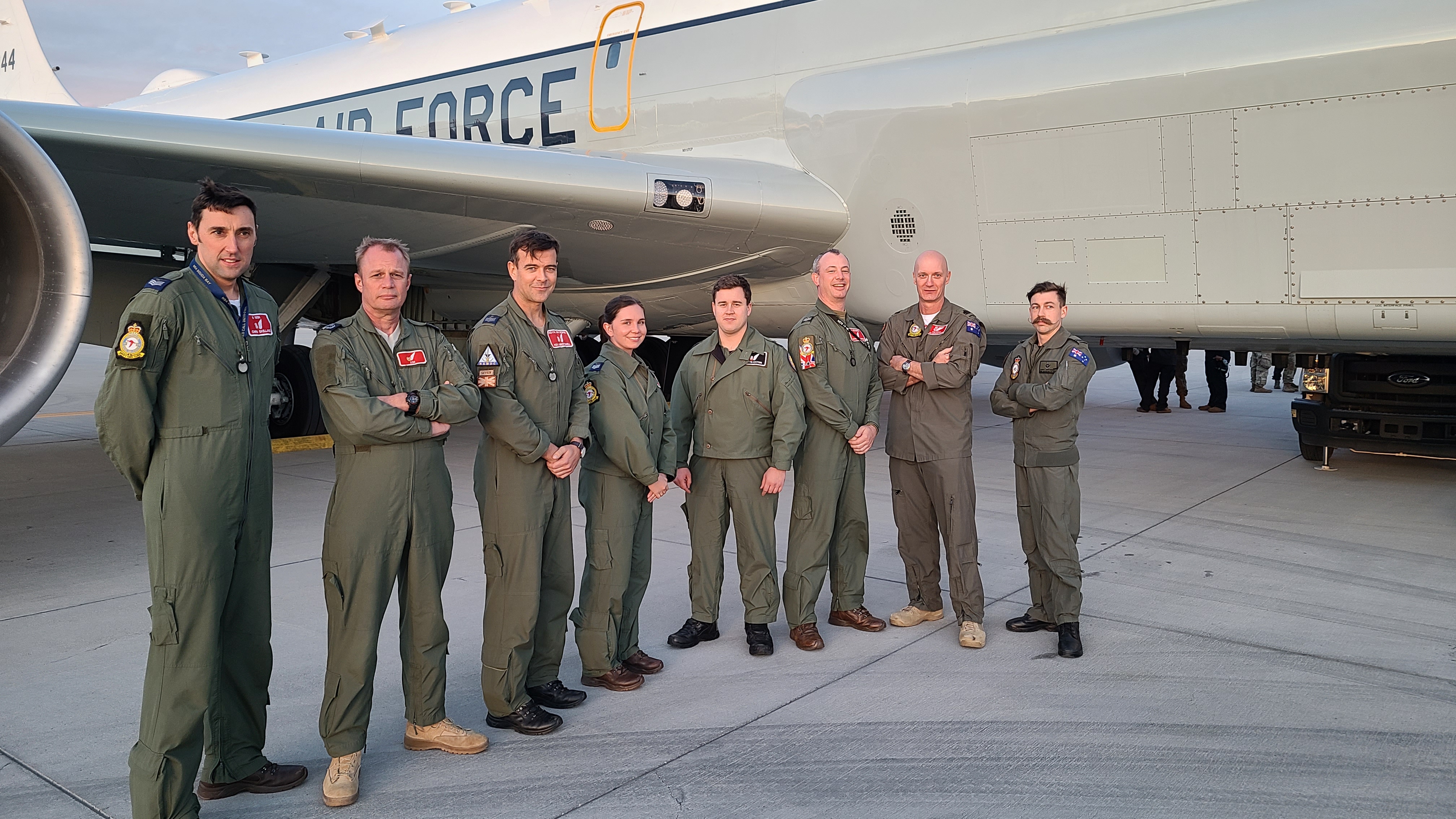 Image shows military personnel standing in front of a Rivet Joint aircraft.