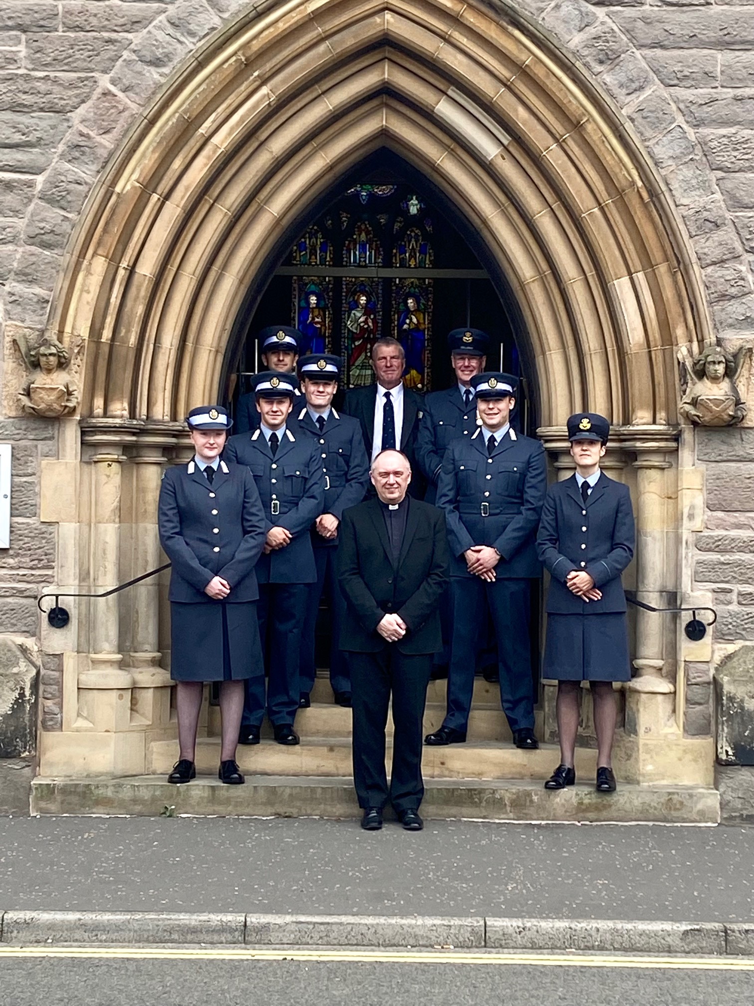 Image shows aviators standing under the archway entrance way to the cathedral, with the Reverend.