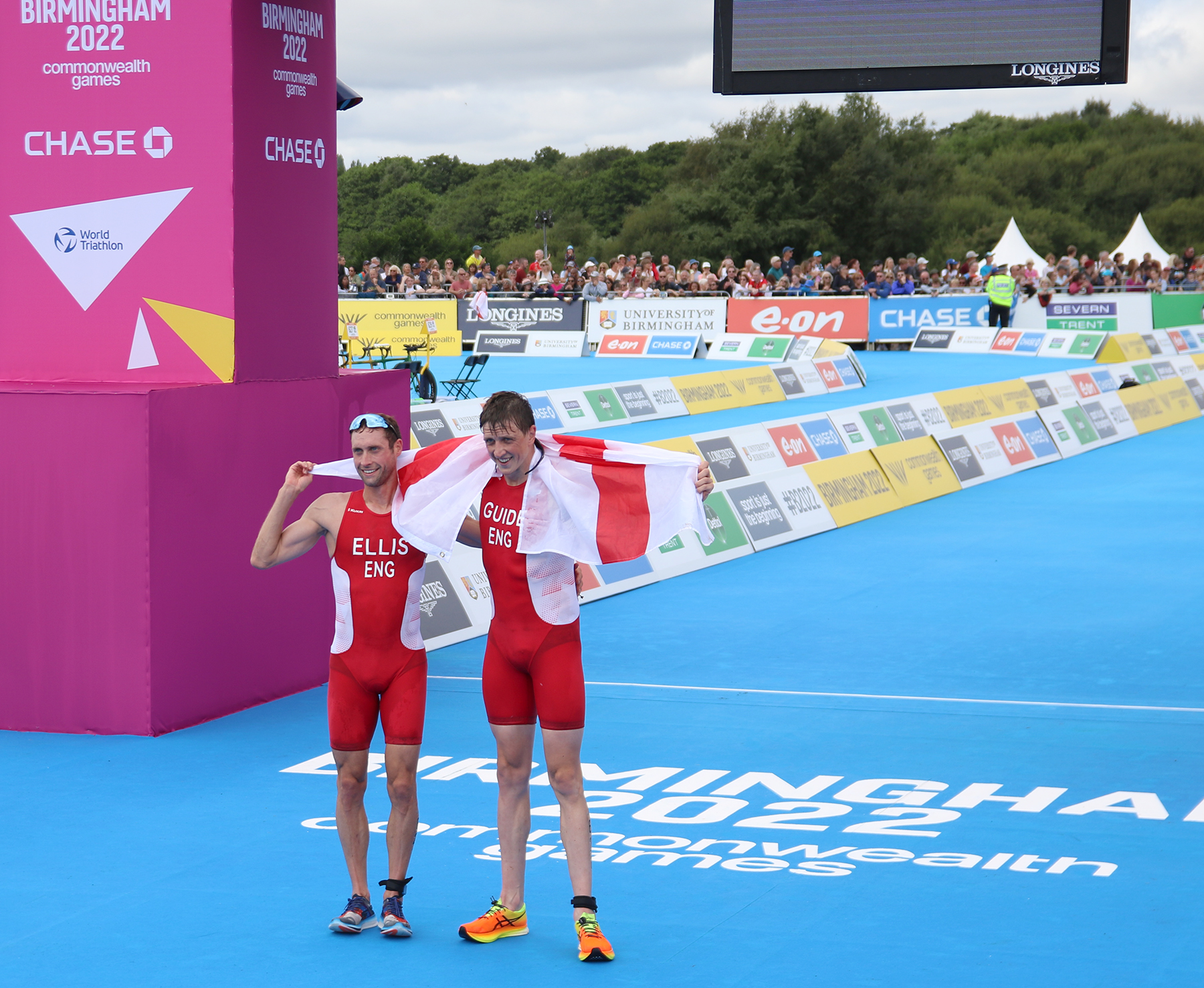 Image shows runners at the finish line, holding England flag.