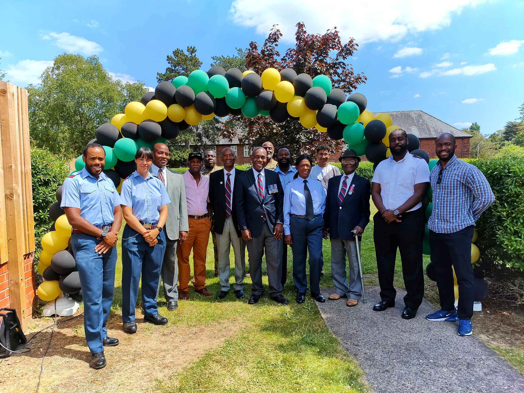 Jamaican aviators smiling under arc of balloons in the colours of the Jamaican flag.