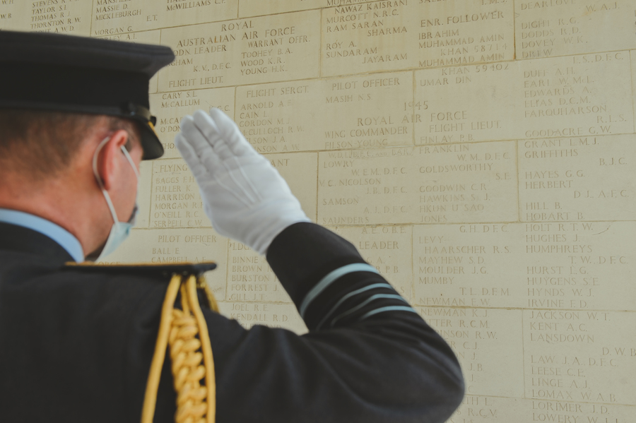 Air Chief Marshal Sir Mike Wigston salutes cemetery wall with names engraved on.