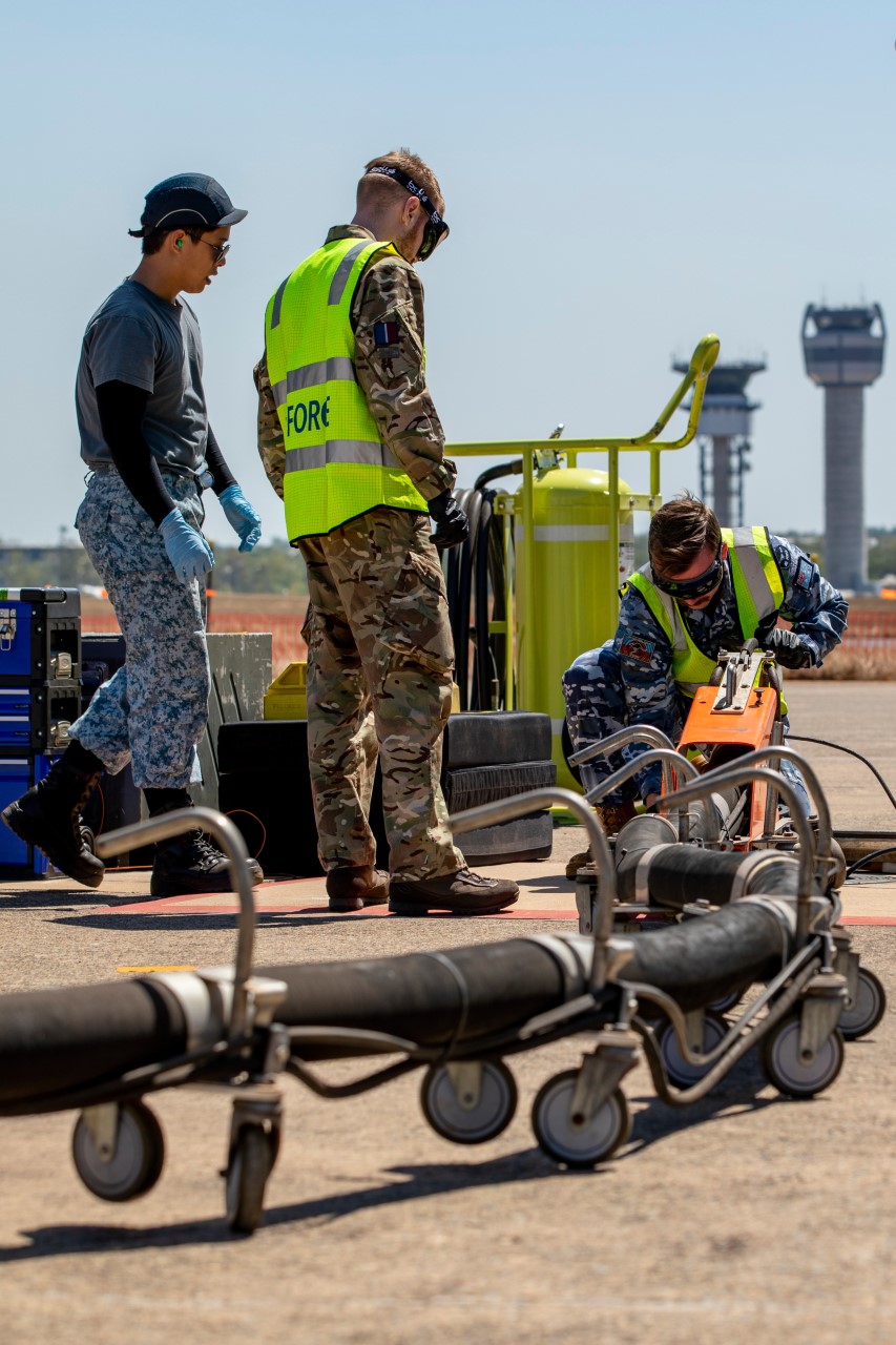 Royal Australian Air Force aviator Leading Aircraftman Thomas Clarke-Kelly (right) and Royal Air Force Air Specialist Class 1 Declan McTrusty (centre) work together to refuel a Republic of Singapore Air Force F-15SG Eagle aircraft, during Exercise Pitch Black 2022 at RAAF Base Darwin