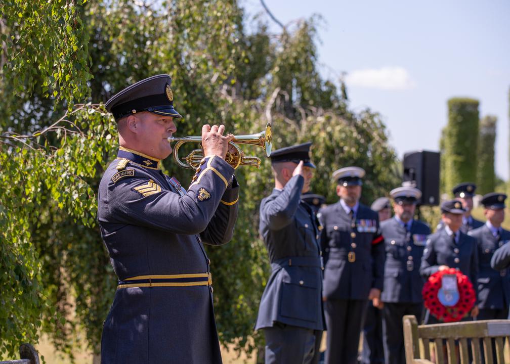 RAF Musician plays bugle while aviators stand during service.