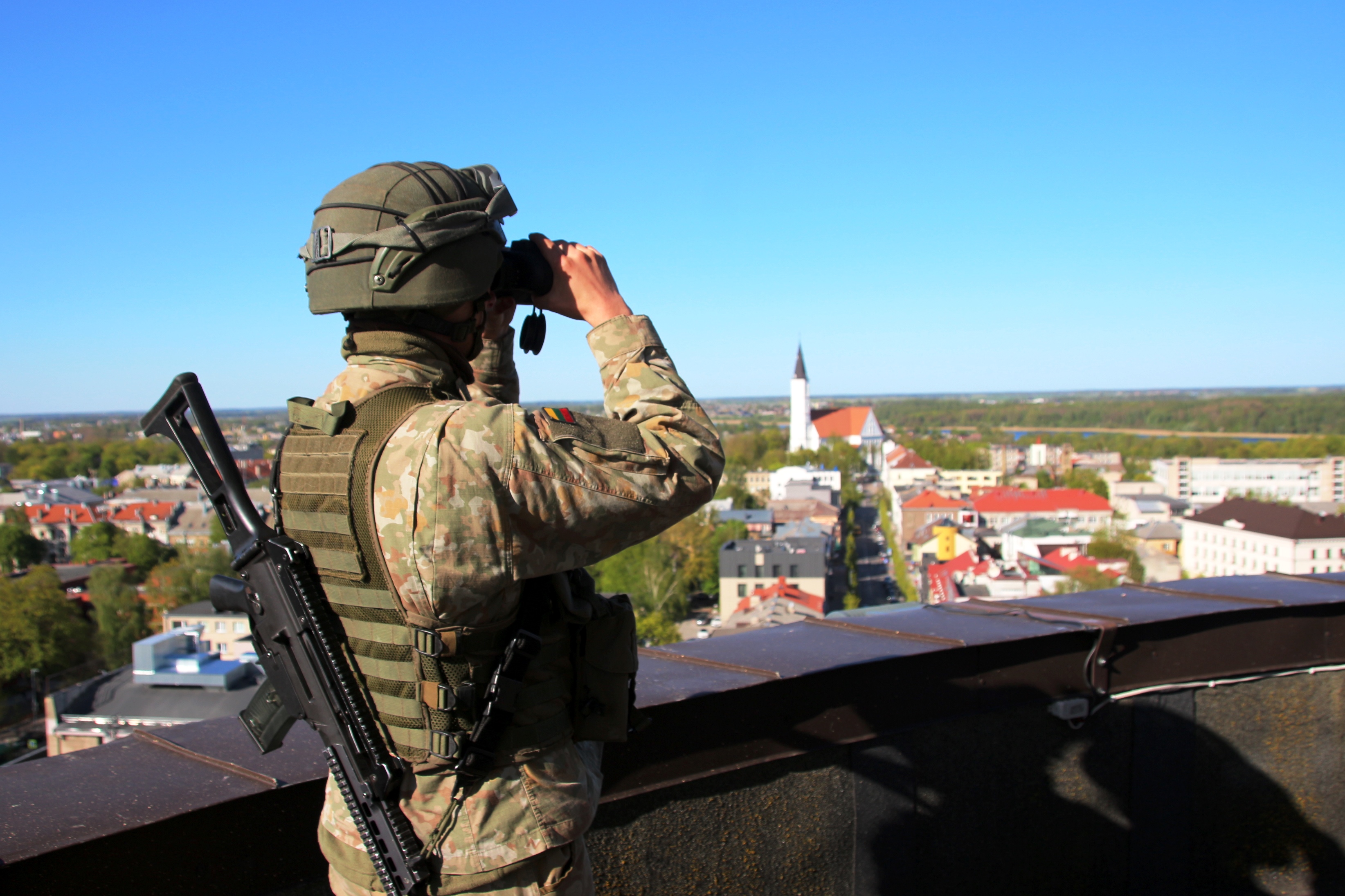 Personnel uses binoculars on rooftop.