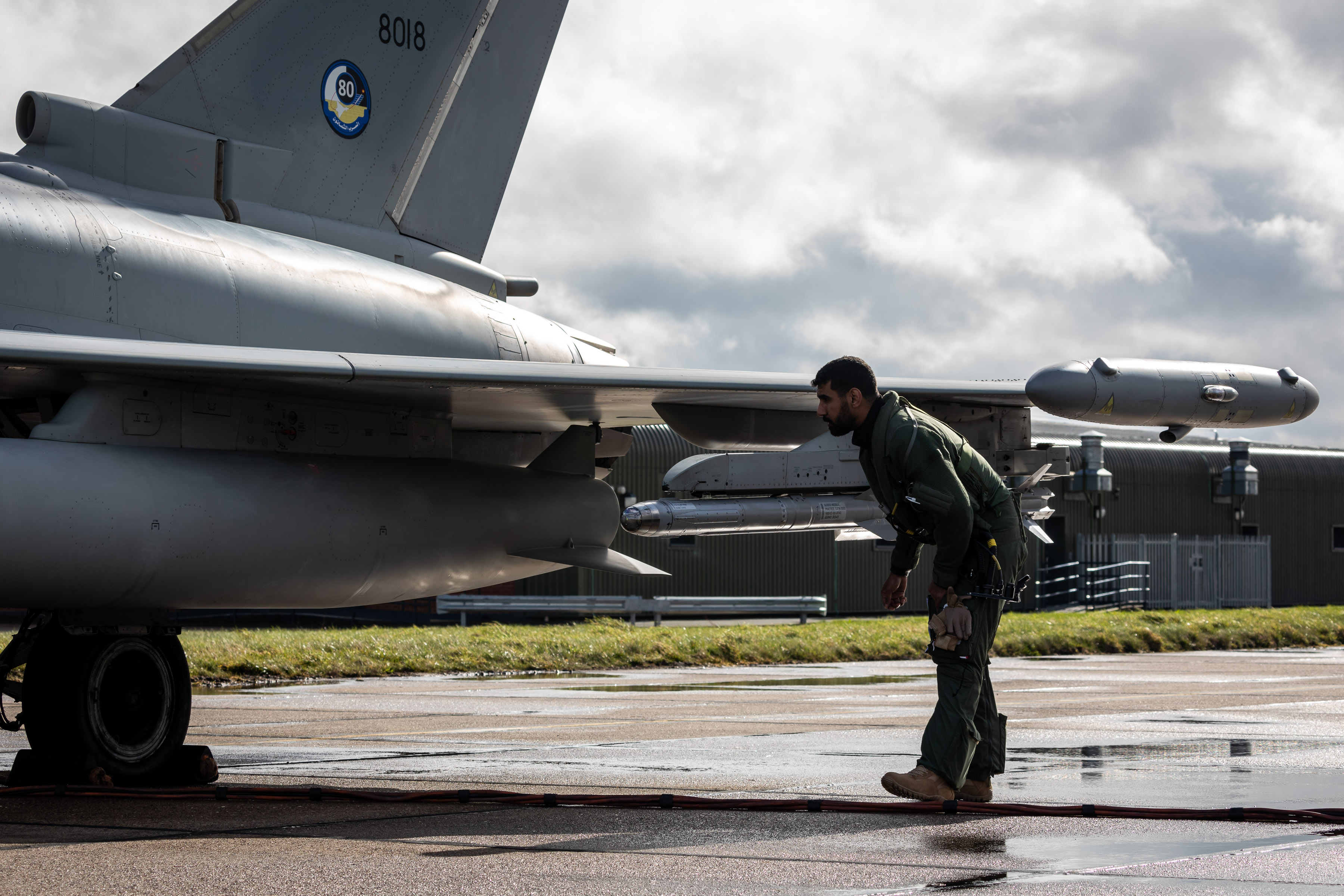 Image shows pilot checking fighter jet on the airfield.