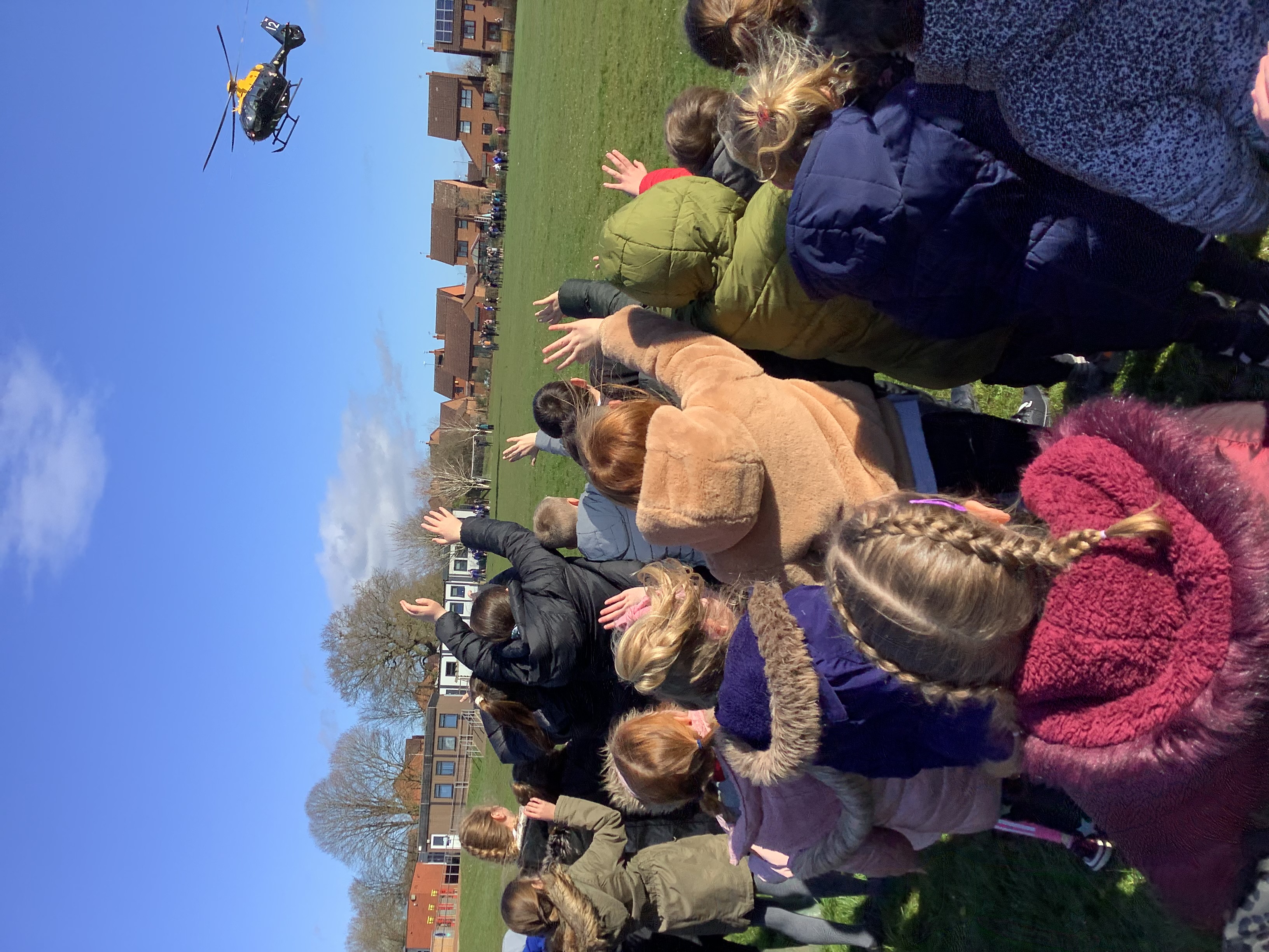 School children wave to Juno helicopter as it rises.