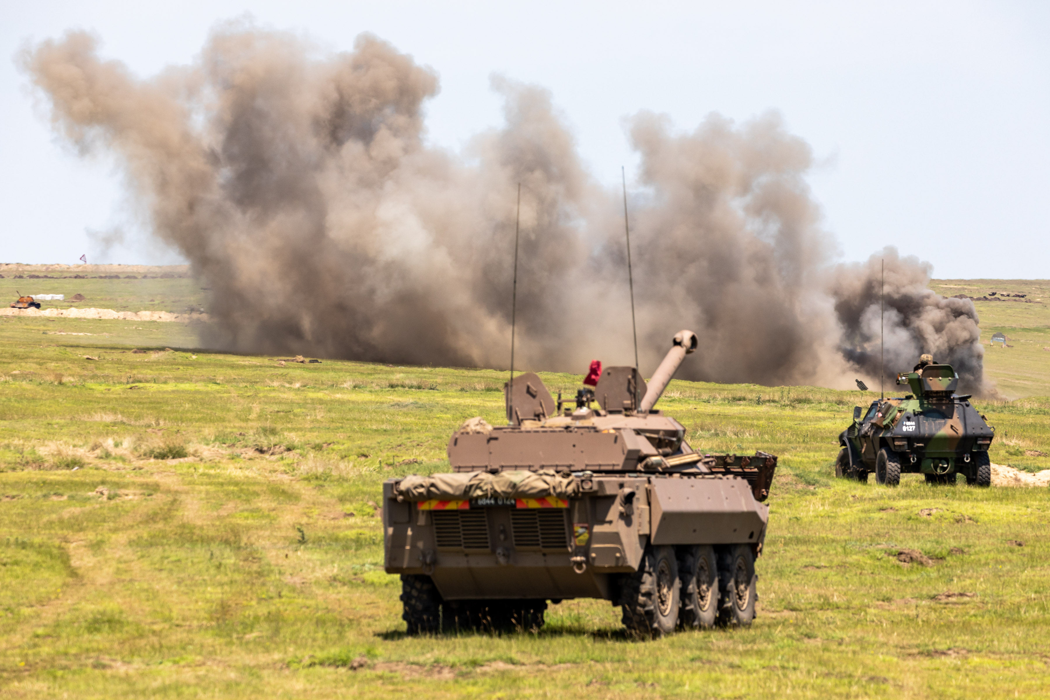 Image shows RAF armoured vehicles firing missiles with dust blowing in the wind. 