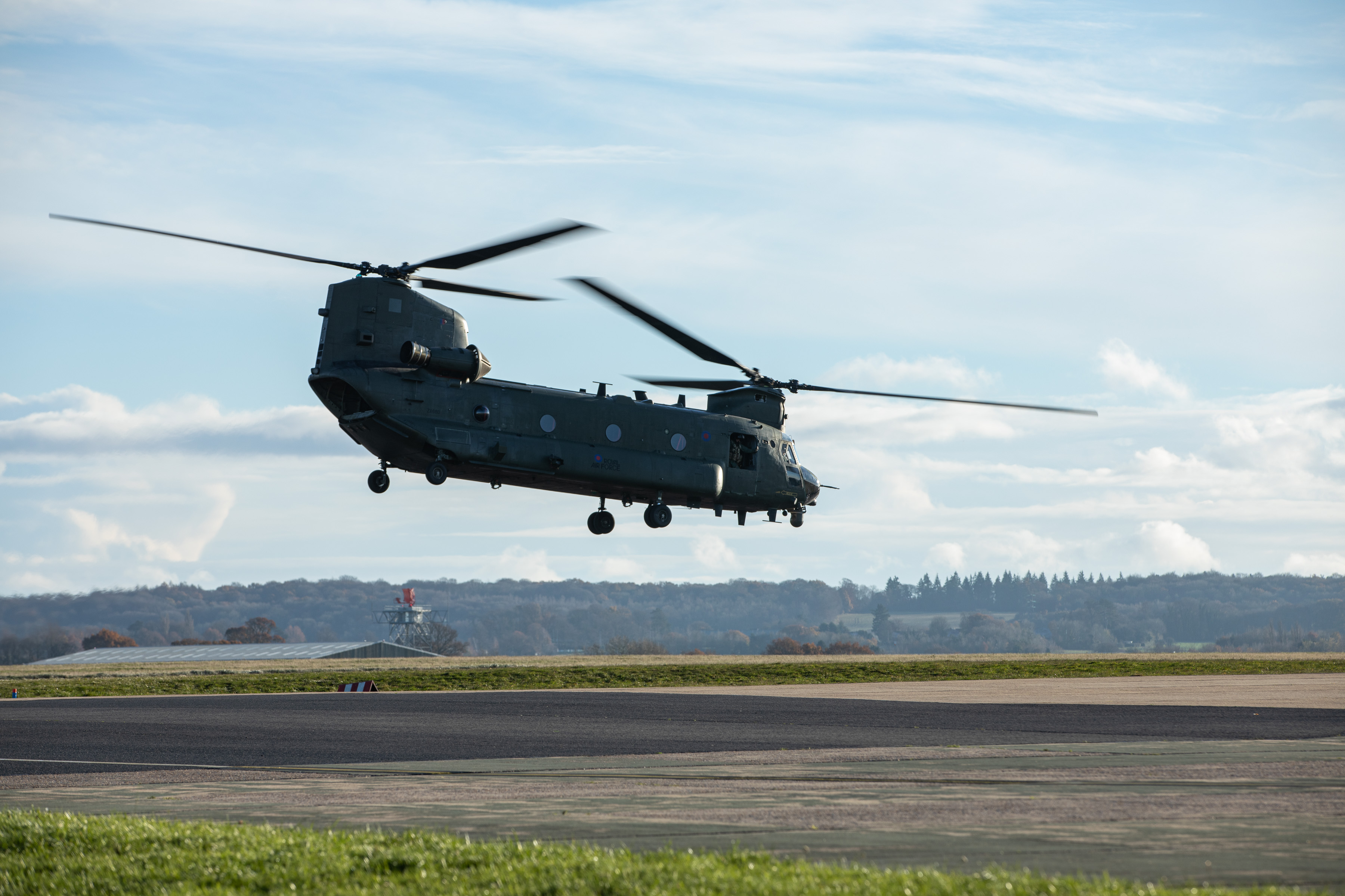 Image shows RAF Chinook helicopter flying low over the airfield.