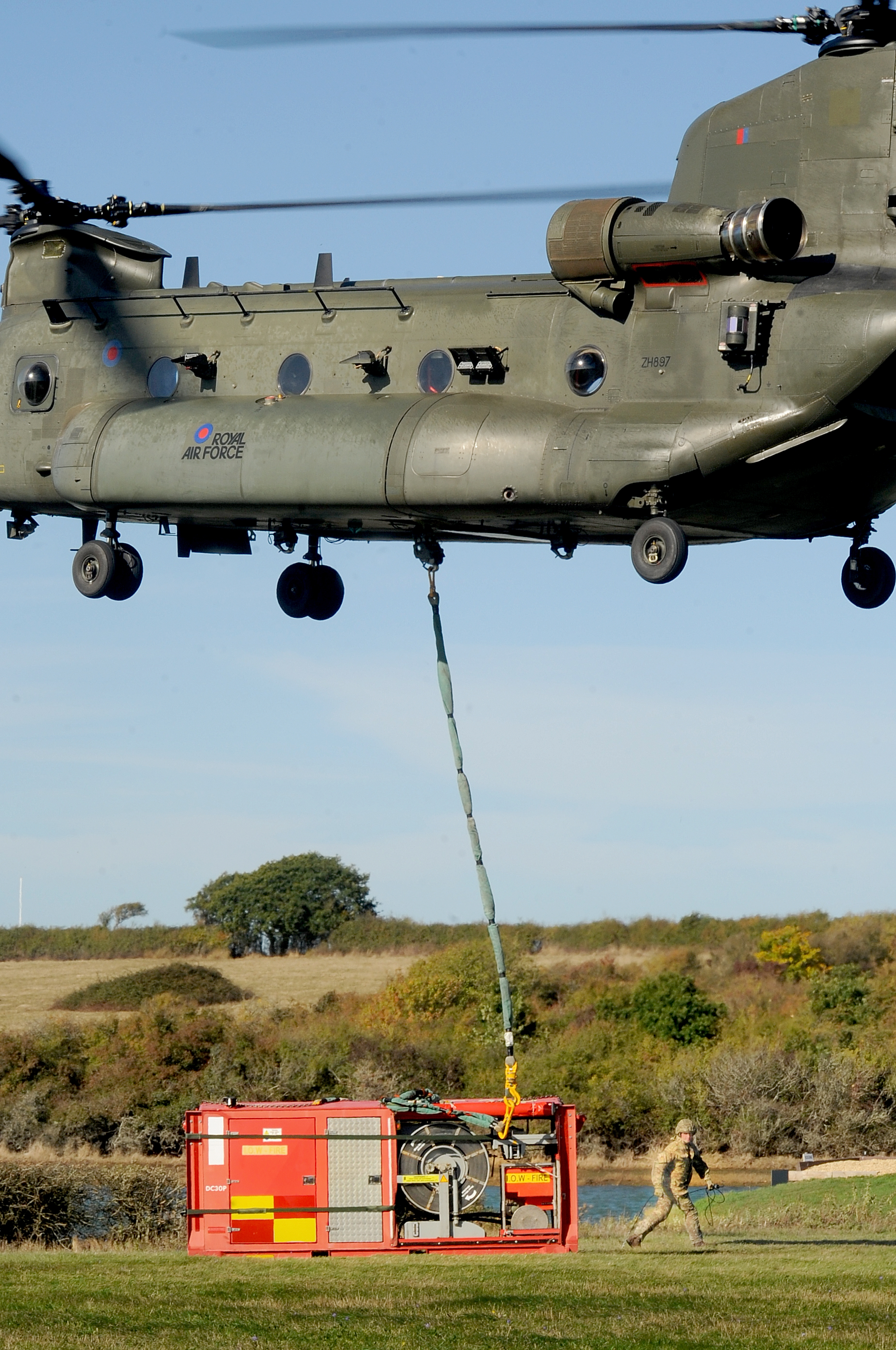 Image shows Chinook dropping under slung cargo to the ground.