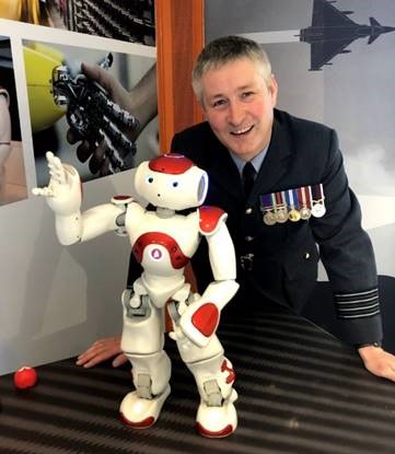 Image shows RAF aviator with a mini robot. 