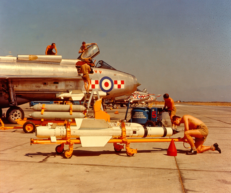 Image shows aged photo of RAF Engineers working on aircraft parts on the airfield.