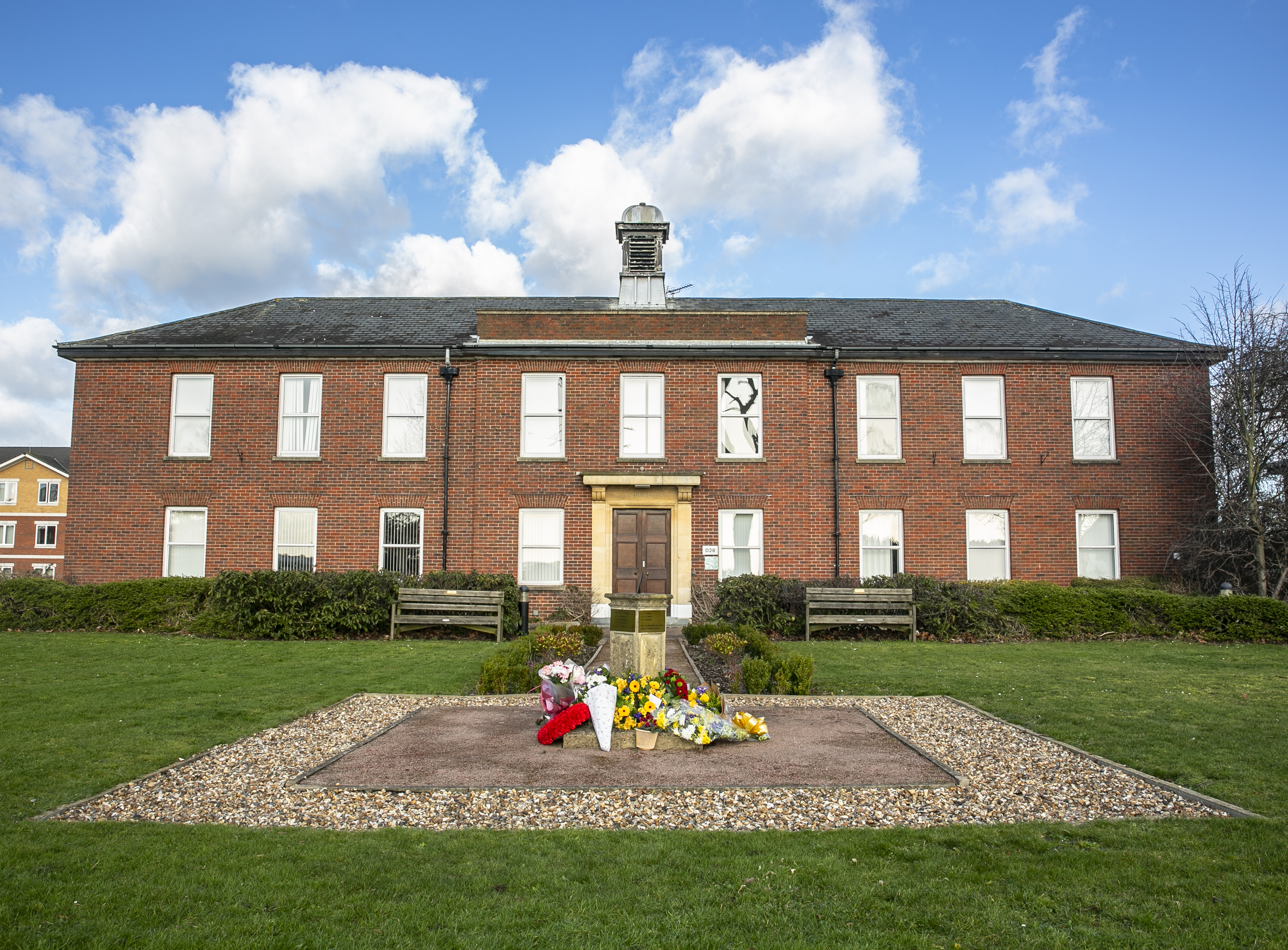 Building with memorial and flowers outside.