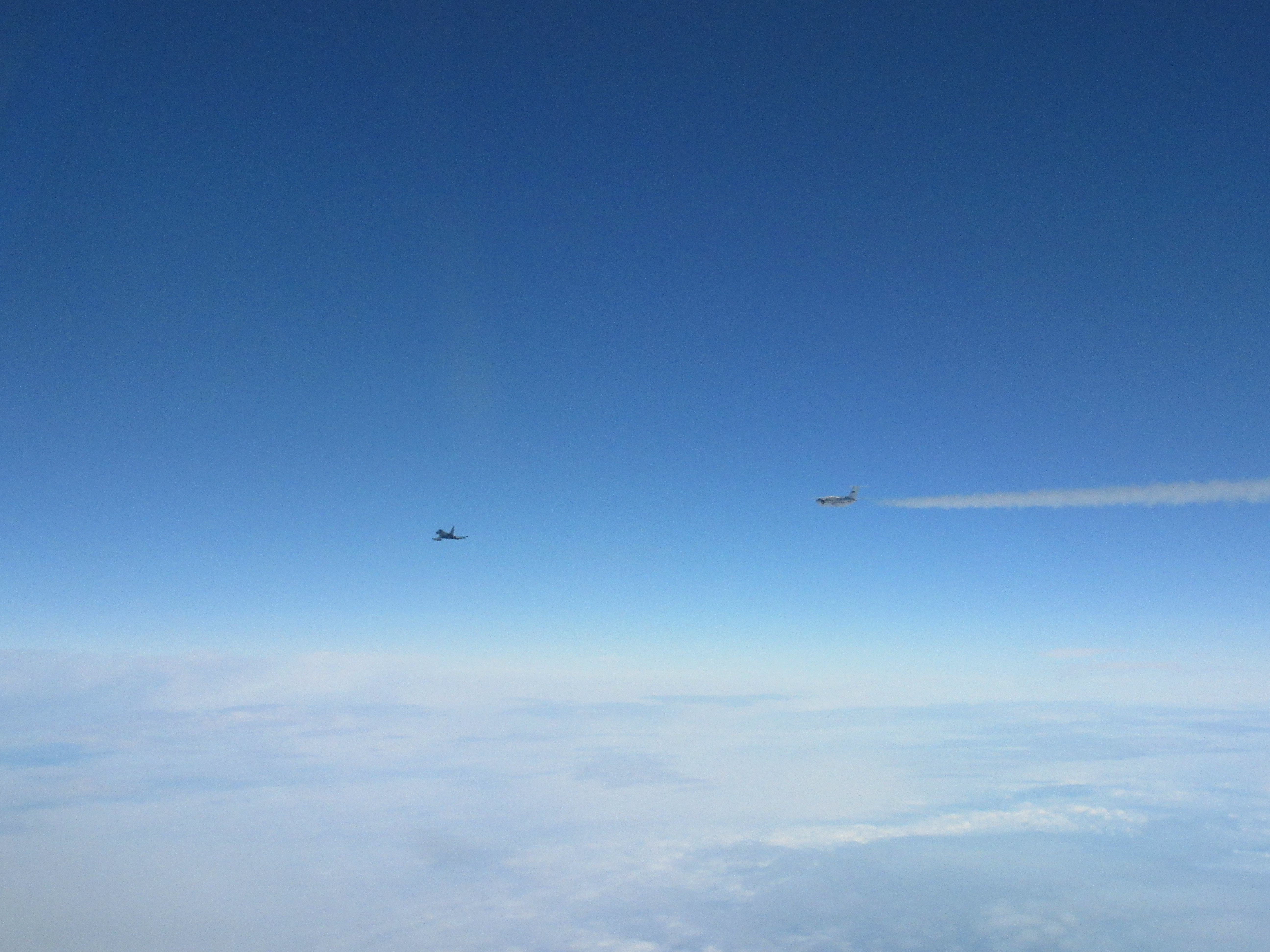 Image shows RAF Typhoon and Russian aircraft in flight above clouds.
