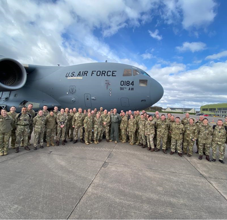 Personnel outside C-17 carrier on the airfield.