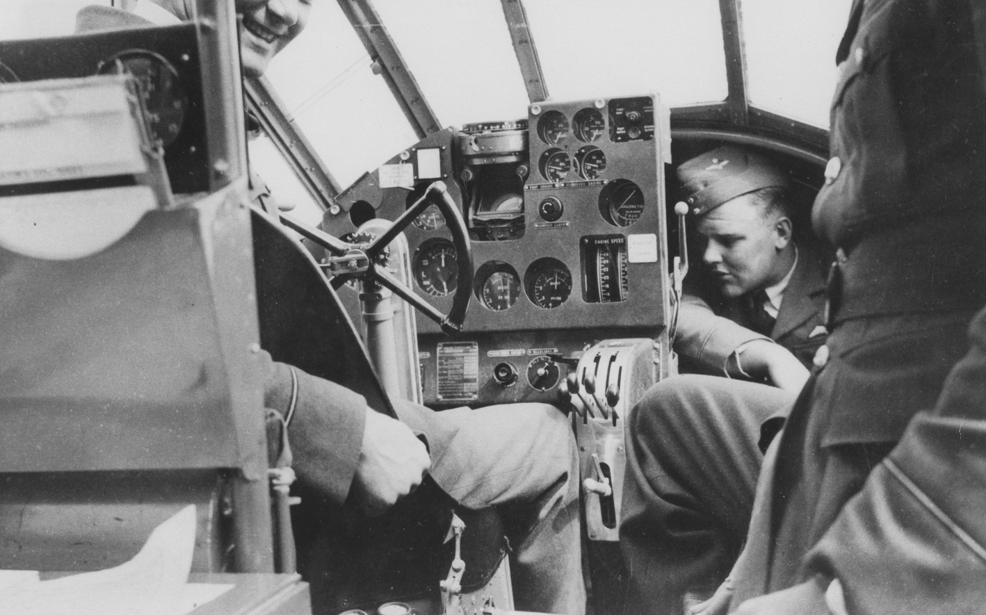 Black and white image shows World War Two RAF personnel inside the cockpit of an Anson aircraft.