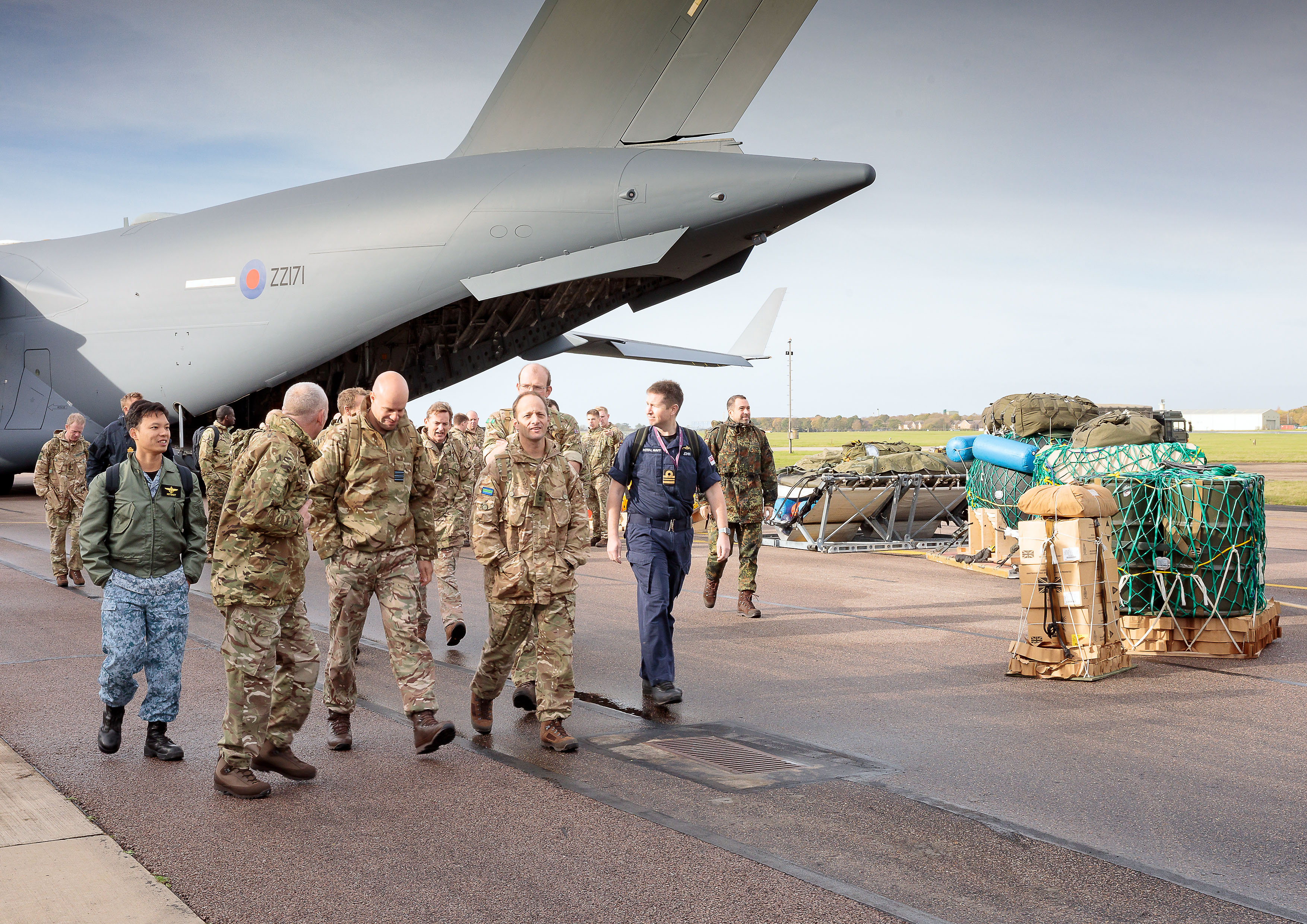 Image shows RAF aviators walking across the airfield away from the Globemaster and cargo crates