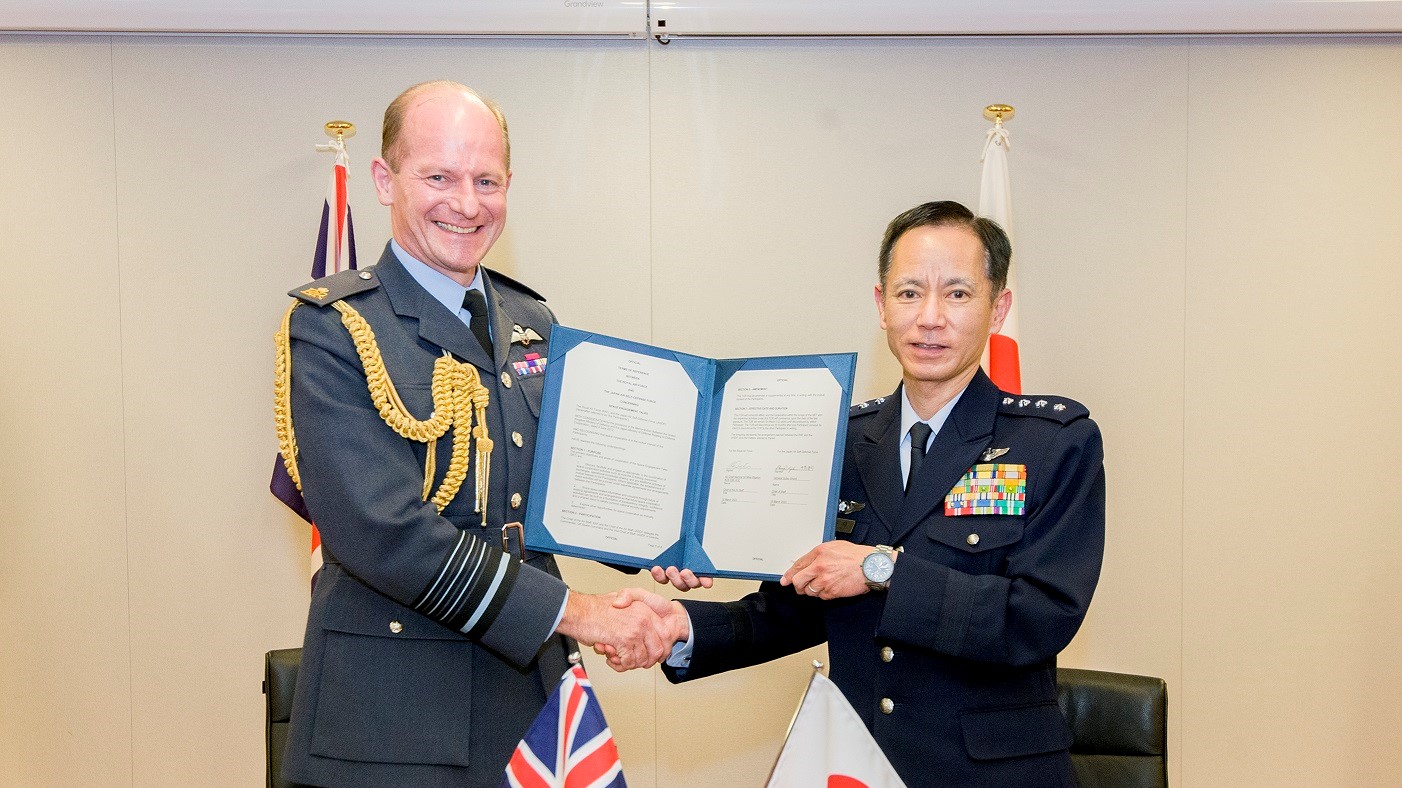 Image shows RAF Chief of Air Staff with Japan Air Self Defence Force Commander shaking hands and holding document.