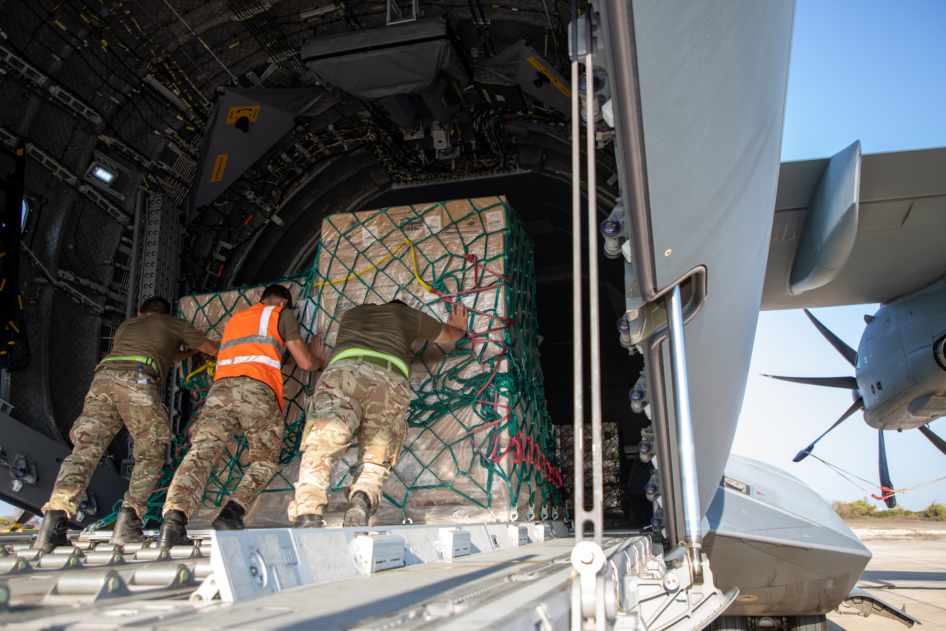 Specialist movers push crate onto Globemaster C-17 loading space.
