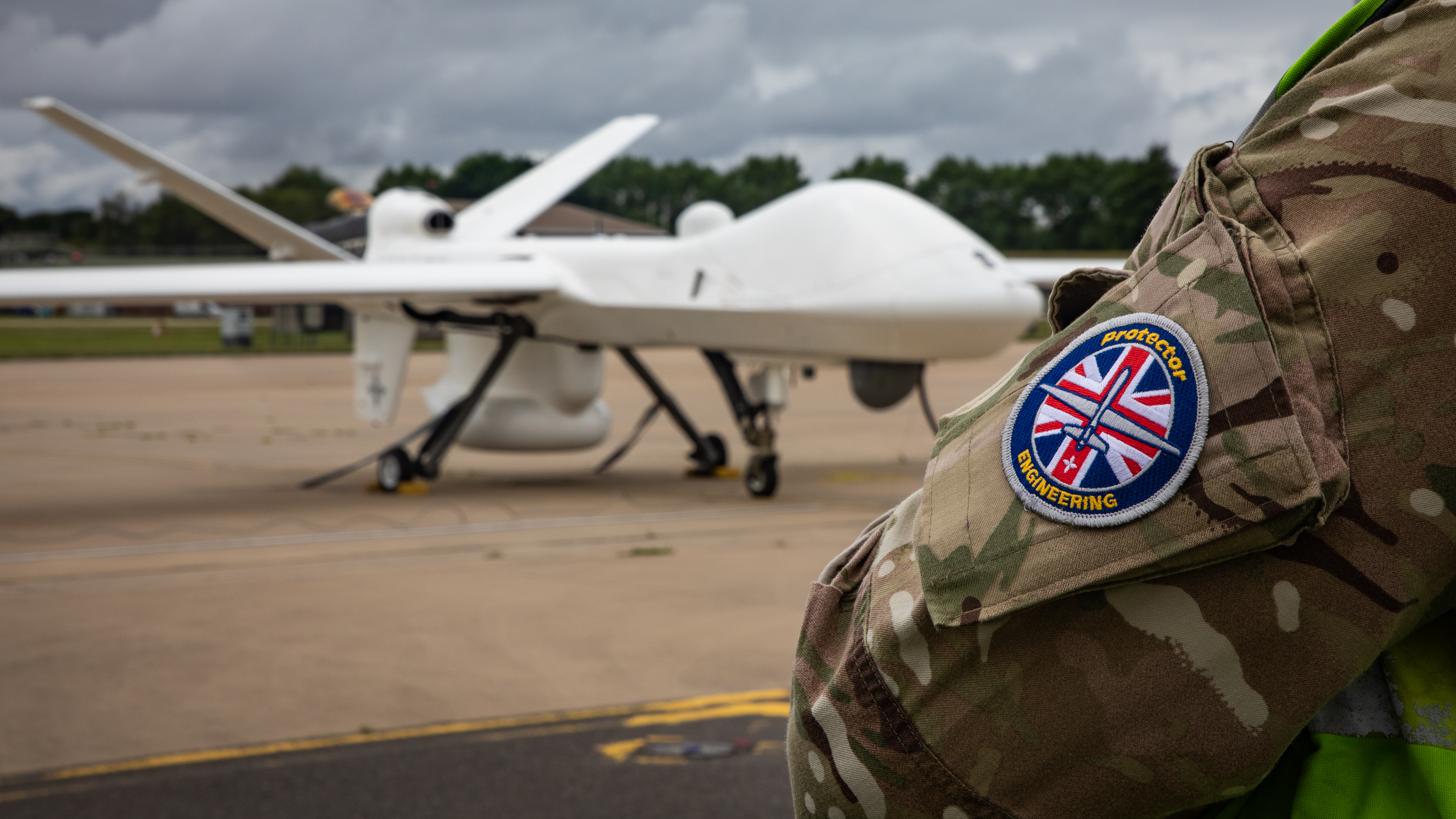 Image shows Protector aircraft on the airfield, with RAF aviator arm patch in shot. 