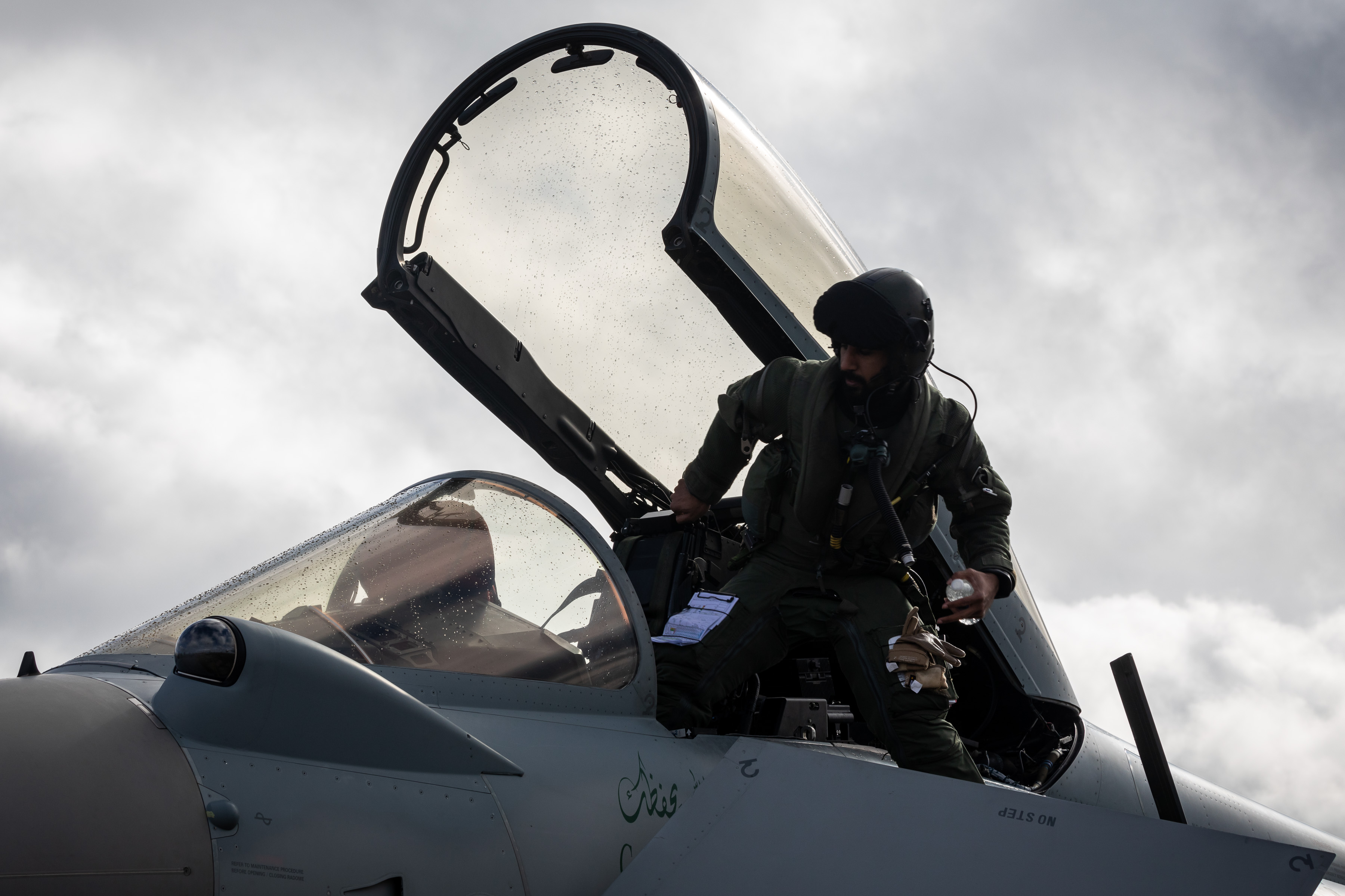 Image shows pilot climbing out of the cockpit of fighter jet.