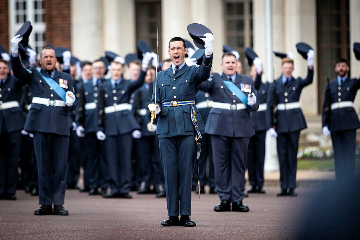 Image shows RAF aviators on graduation, taking their peak caps off..