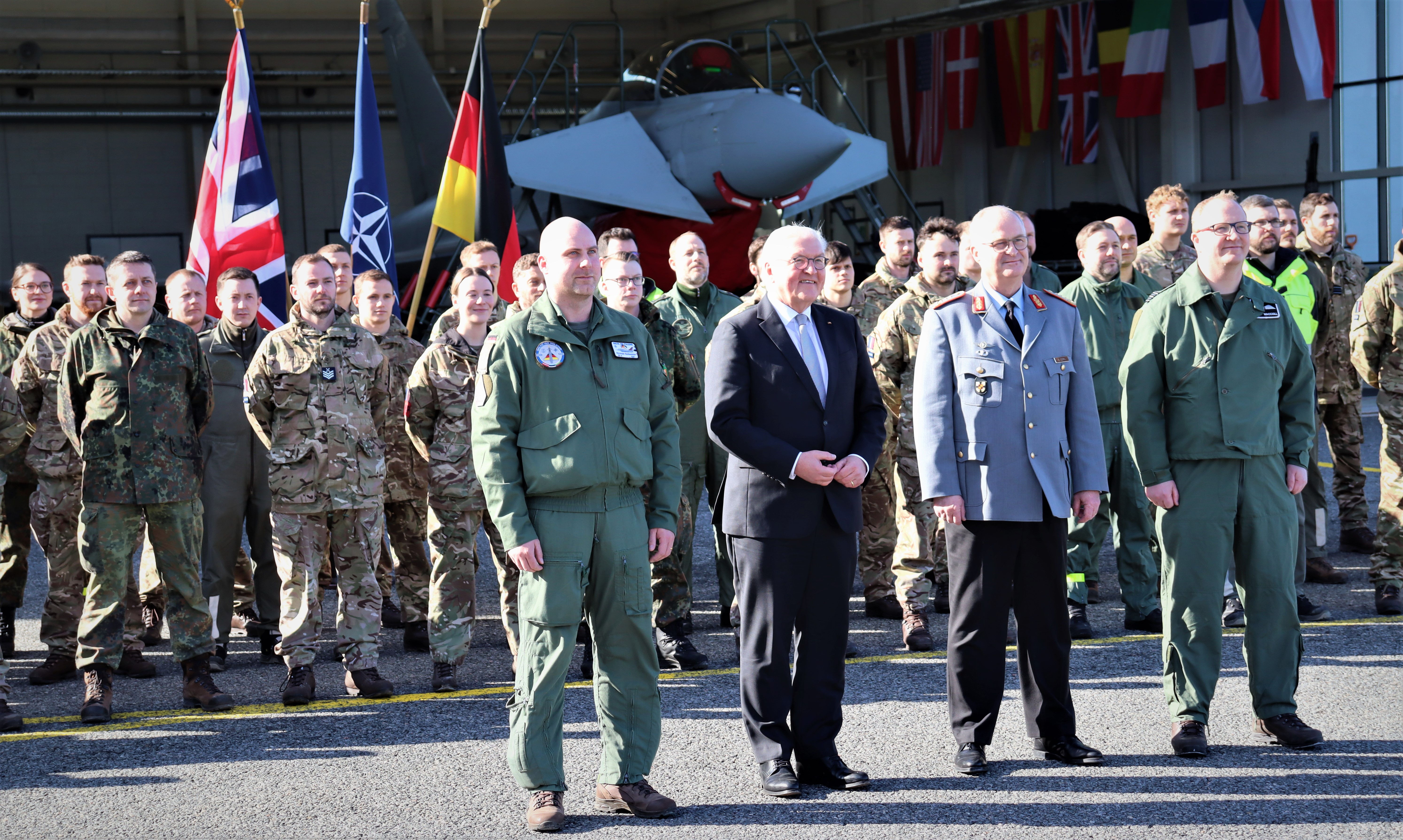 Image shows RAF and German personnel standing with the German President by a hangar.