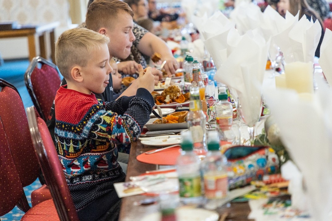 Image shows young children eating a Christmas Dinner