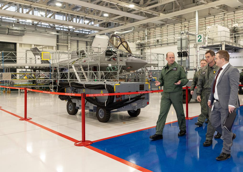 Image shows RAF personnel inside a hangar walking past a Typhoon. 