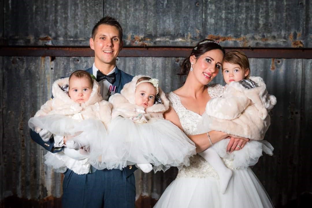 Image shows Helen and her husband holding their three daughters on their wedding day.