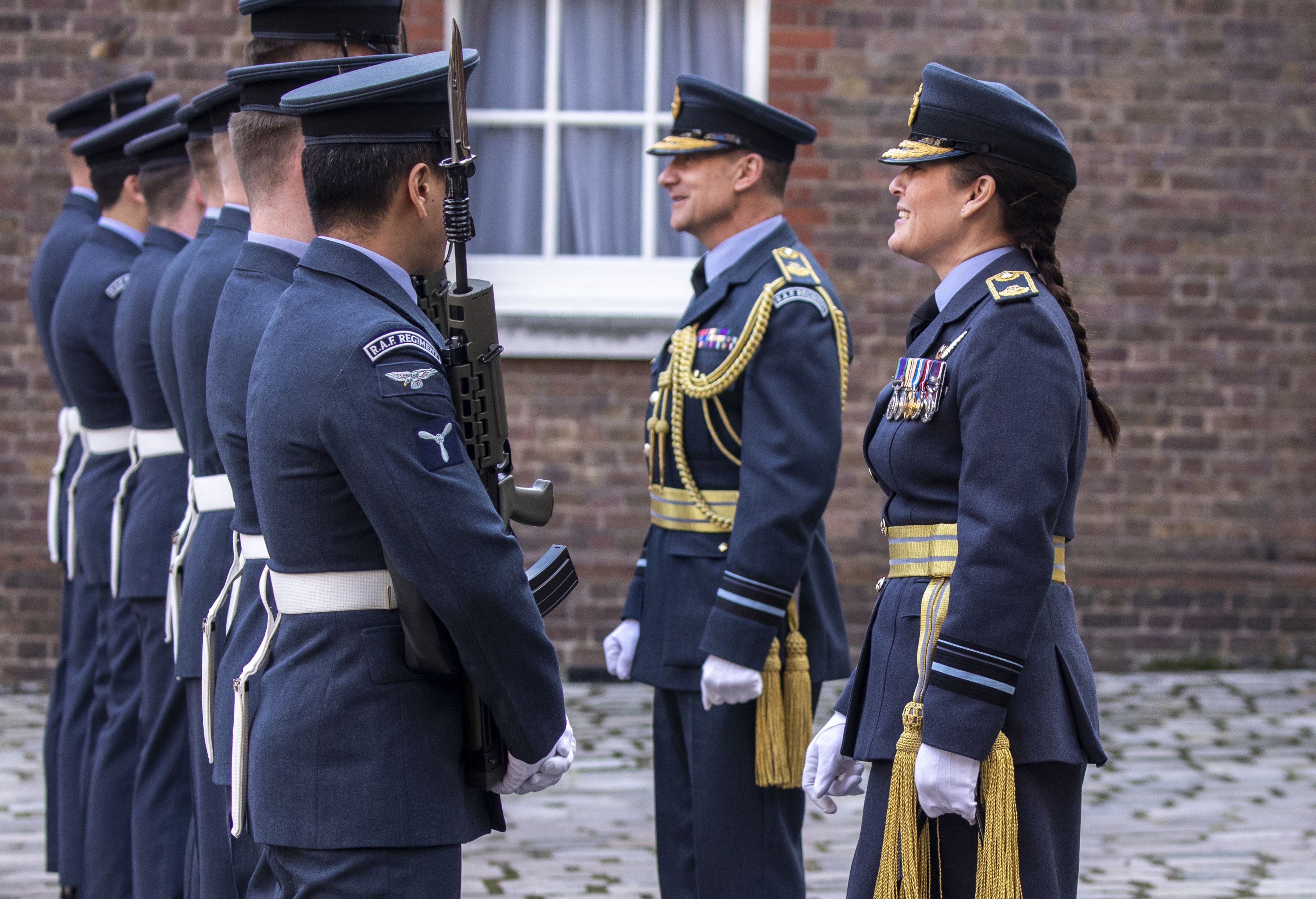 Personnel smile in front of the Queen's Colour Squadron on parade.