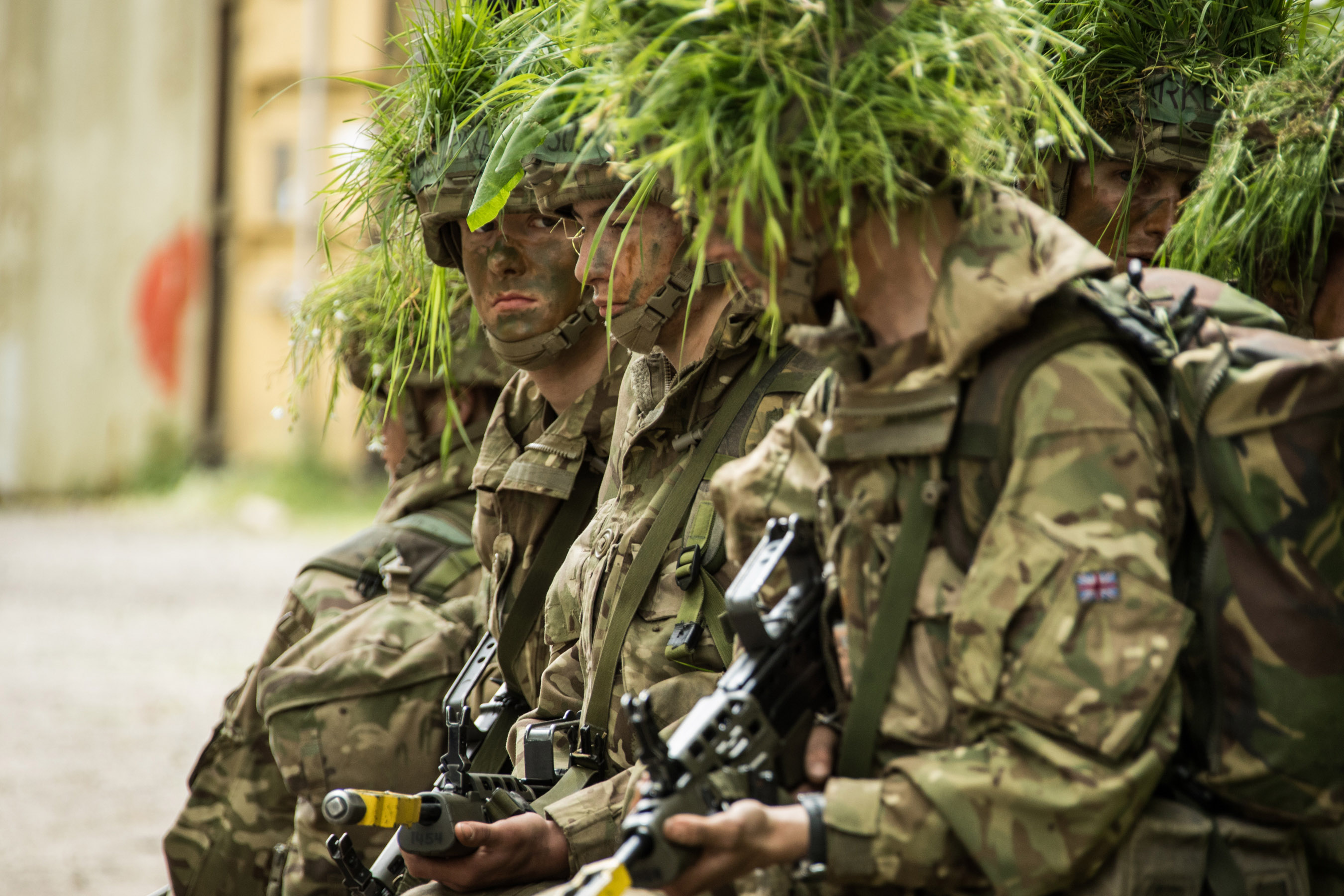Personnel in camouflage with grass on their heads.