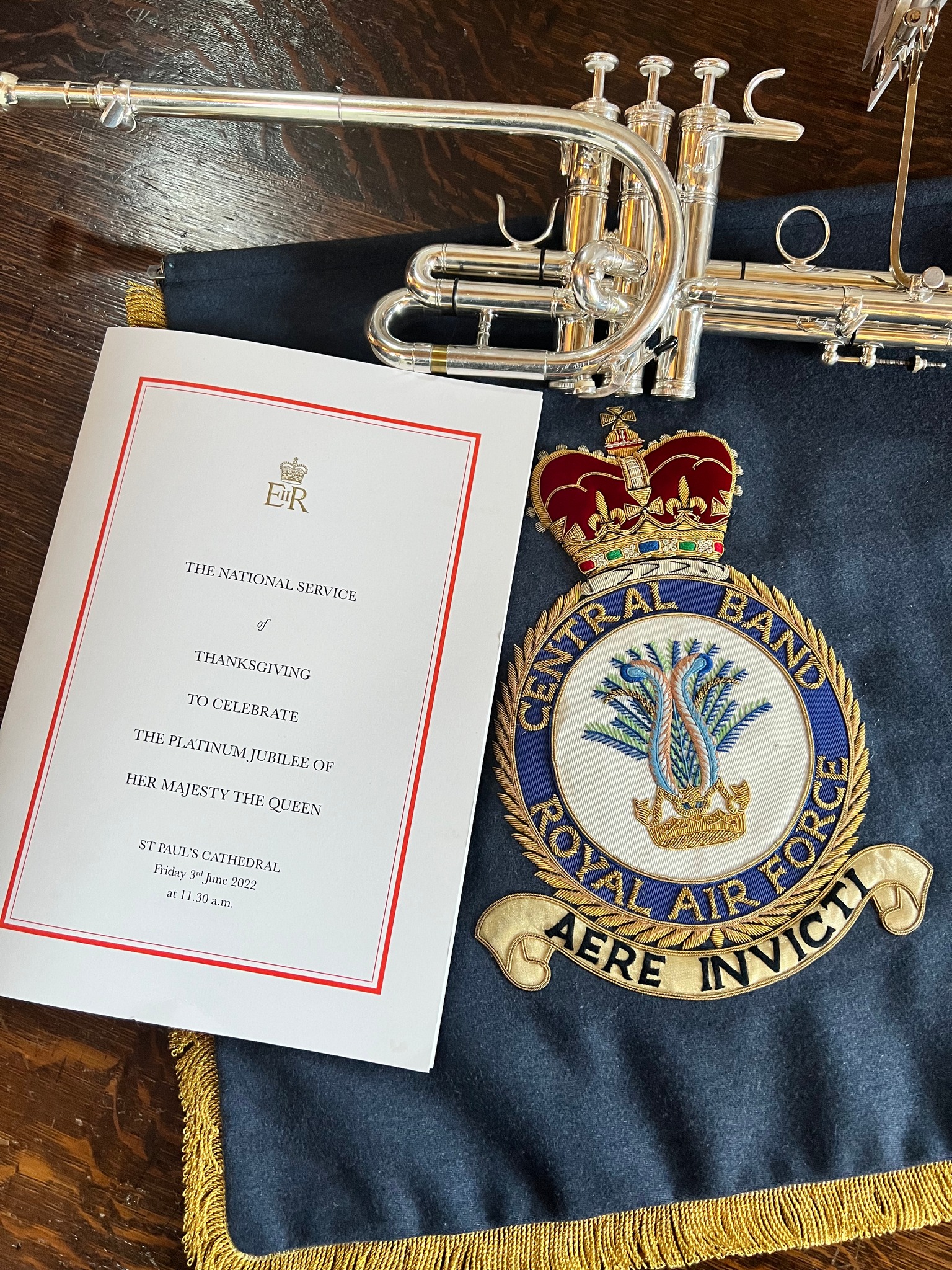Tuba instrument laid on a table, with an RAF Central Band embellished cloth and Thanksgiving booklet.